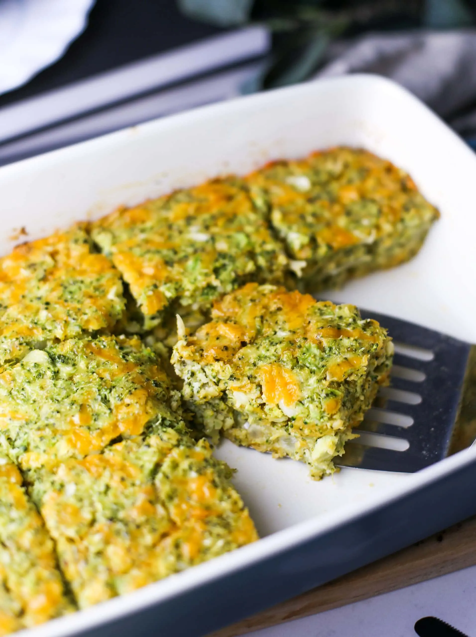 A top angled view of broccoli cheddar squares in a baking dish.