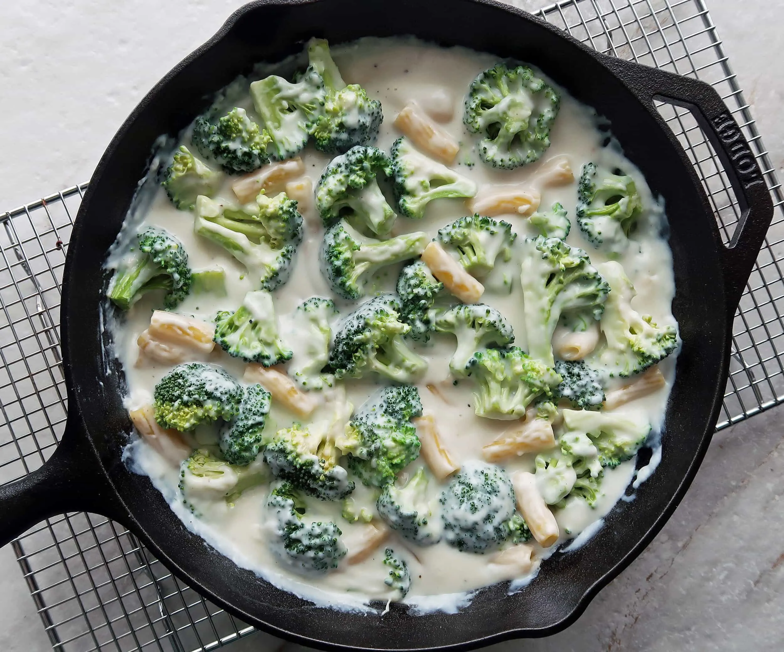 Broccoli, pasta, and milk in a skillet.