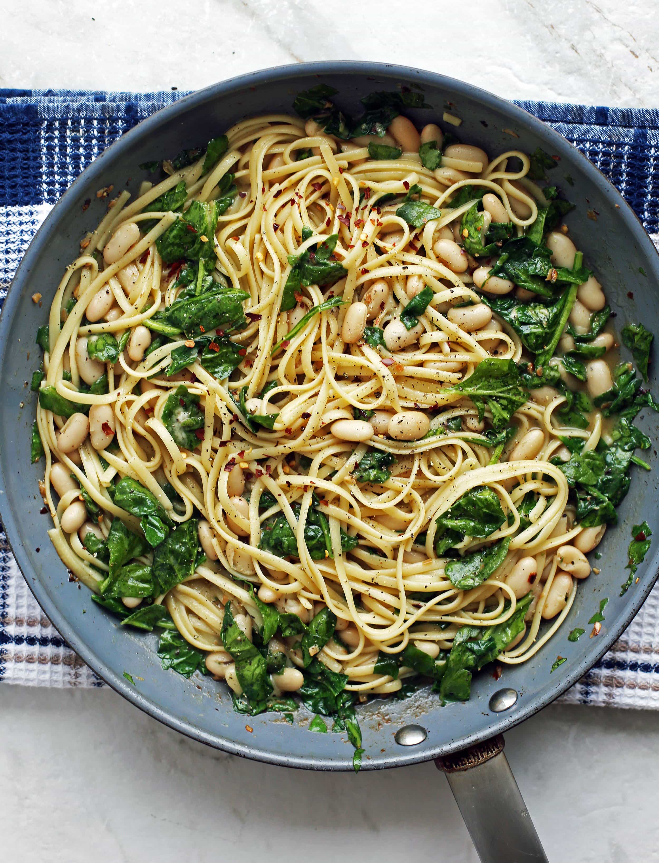 Brown Butter Linguine with White Beans and Spinach in a large light blue skillet..