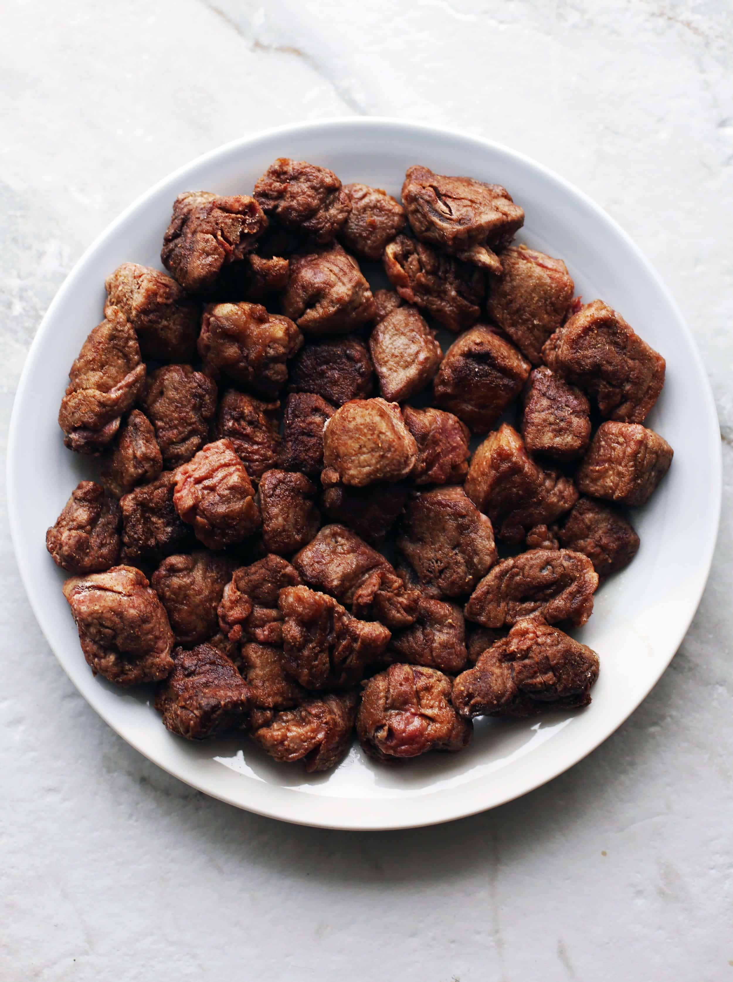 A plate of sliced stewing beef that has been browned in the pot.