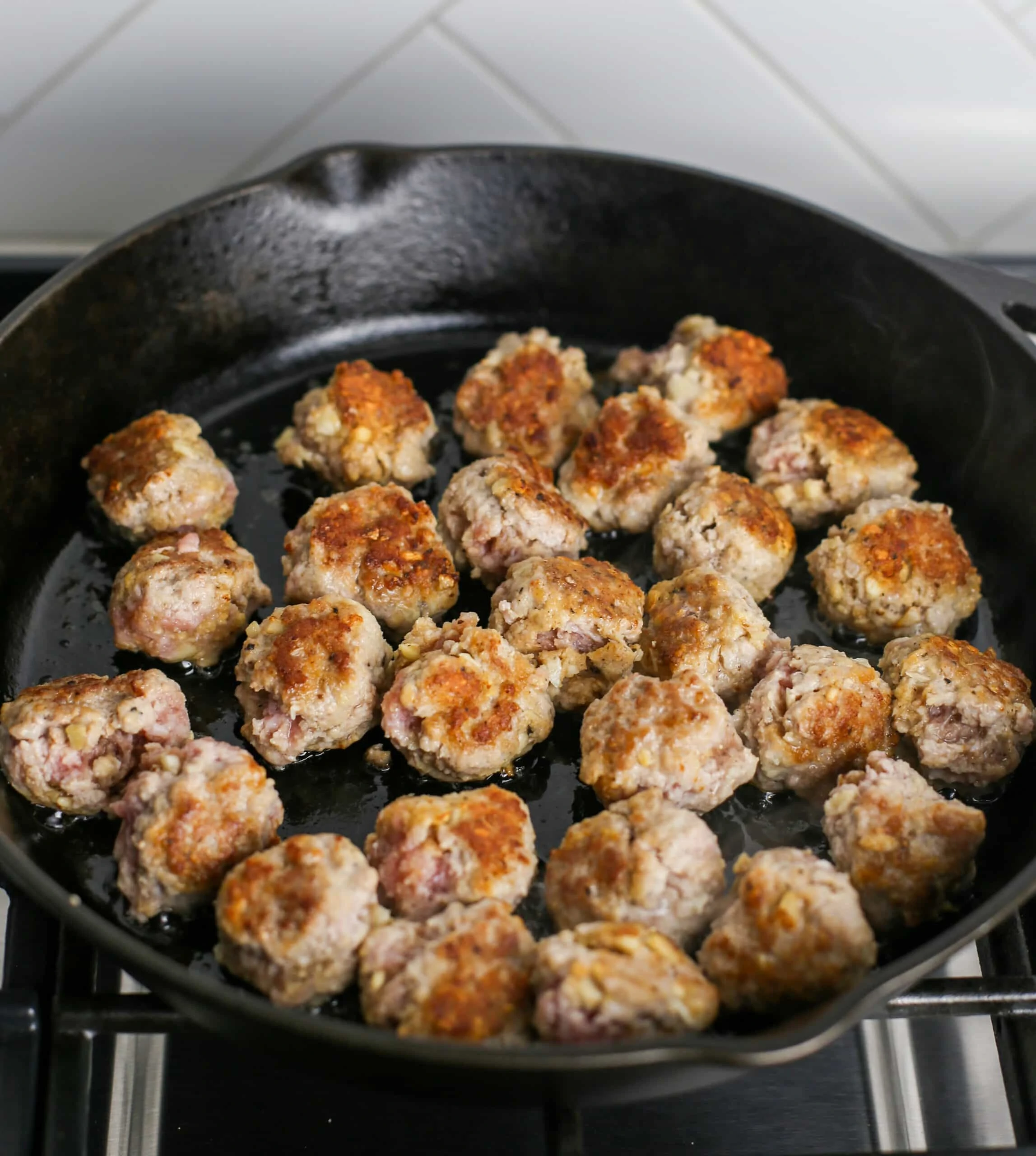 Browned ginger pork meatballs in a large black cast iron skillet.