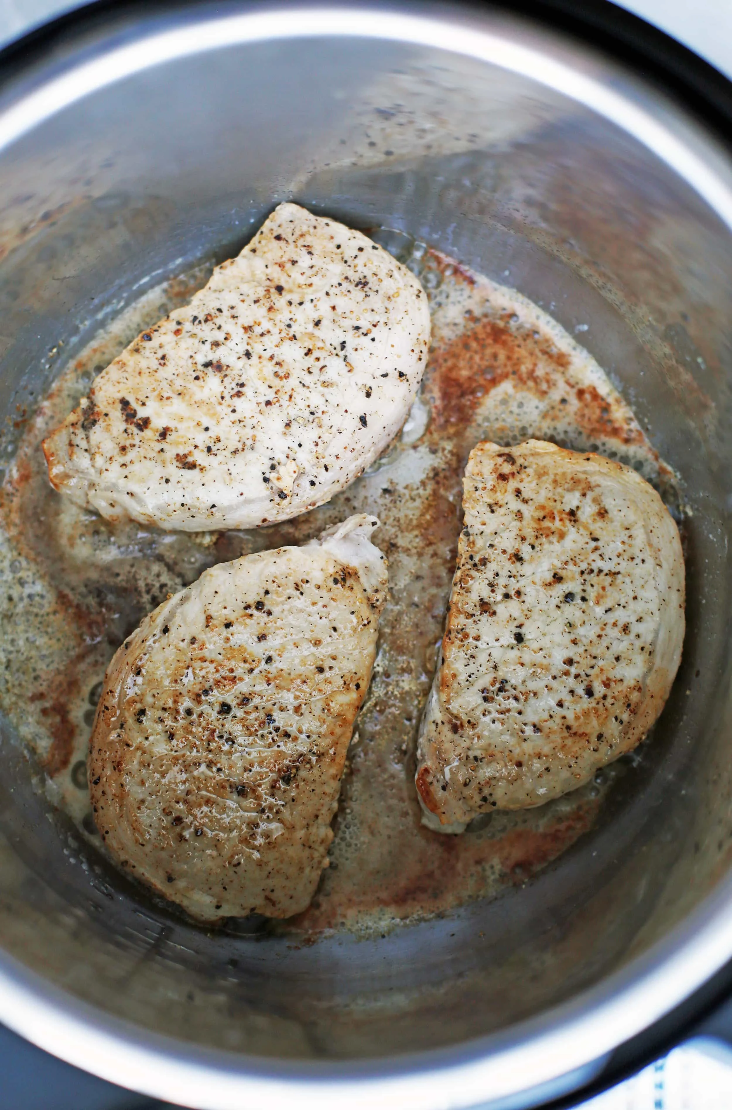 Three browned boneless pork chops in an Instant Pot.