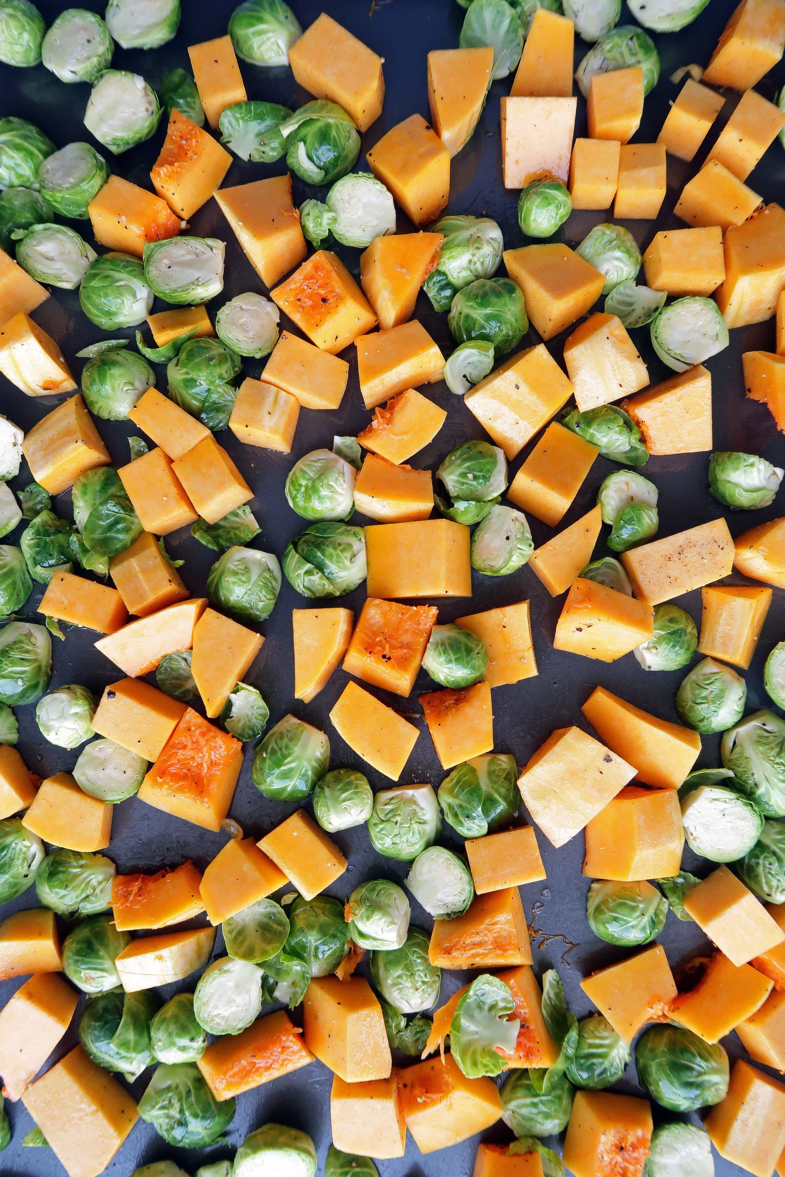 Chopped butternut squash and Brussels in a single layer on a baking sheet.