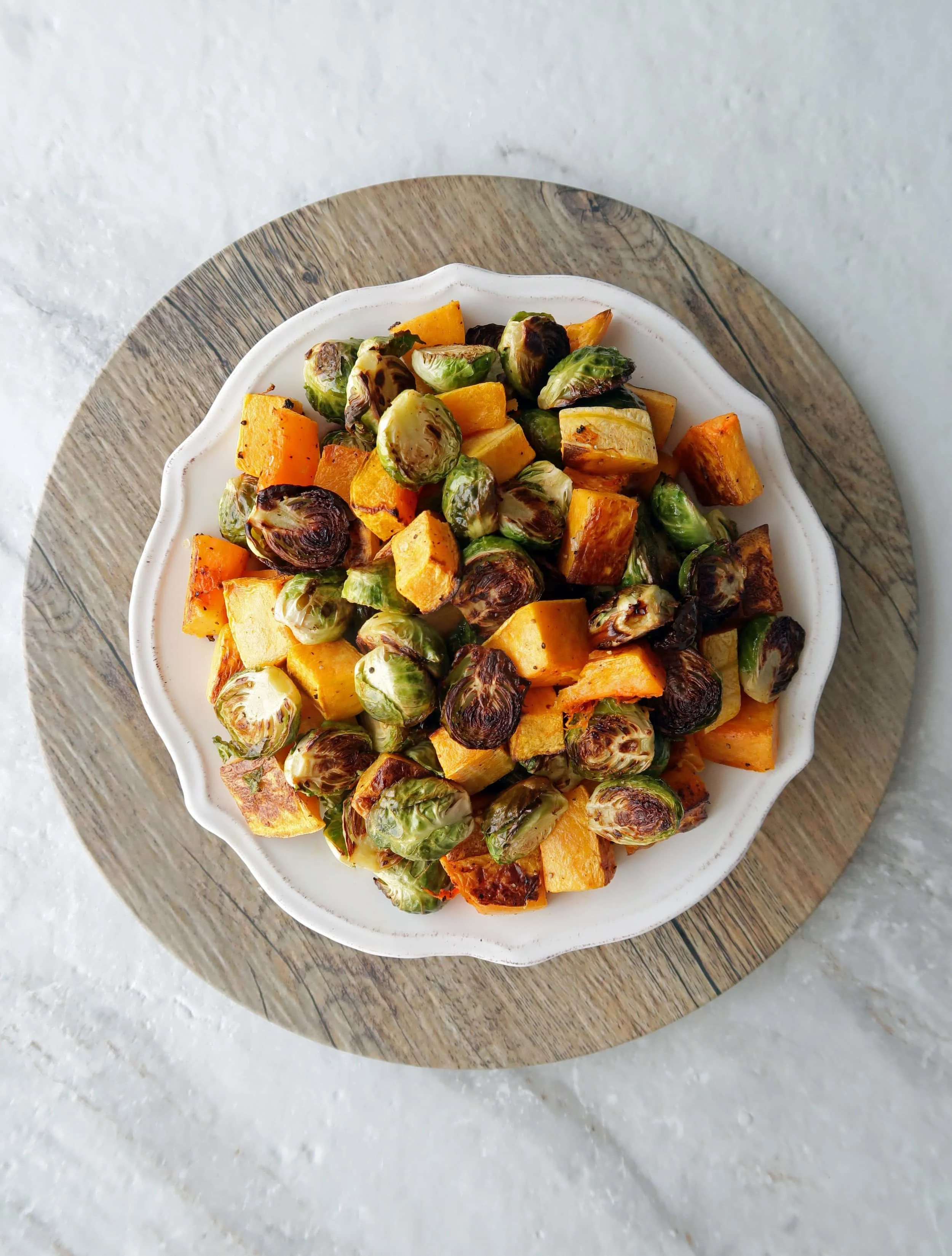 Roasted butternut squash and Brussels sprouts on a white plate.