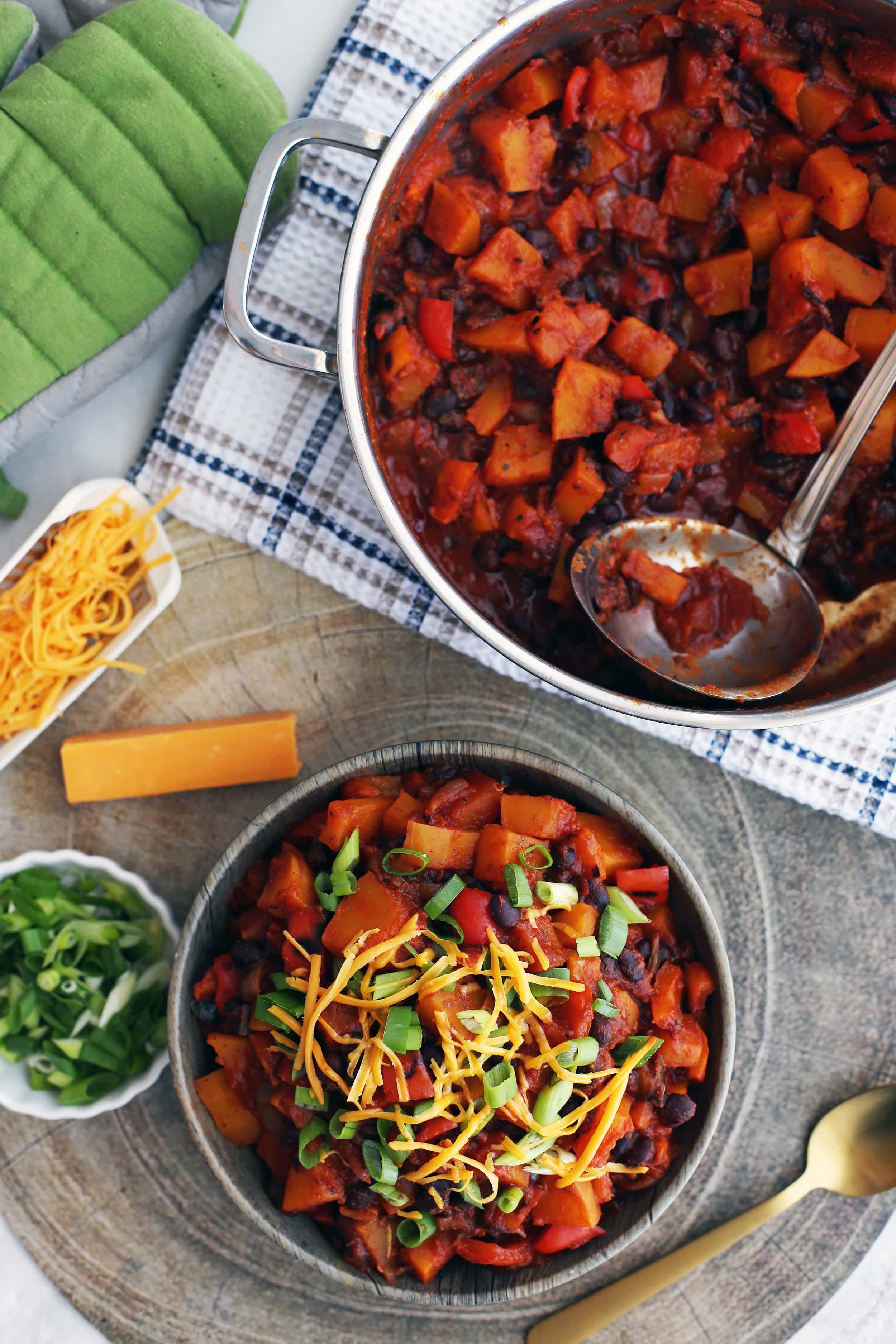 Roasted Butternut Squash and Black Bean Chili in a wooden bowl and in a large metal pot.