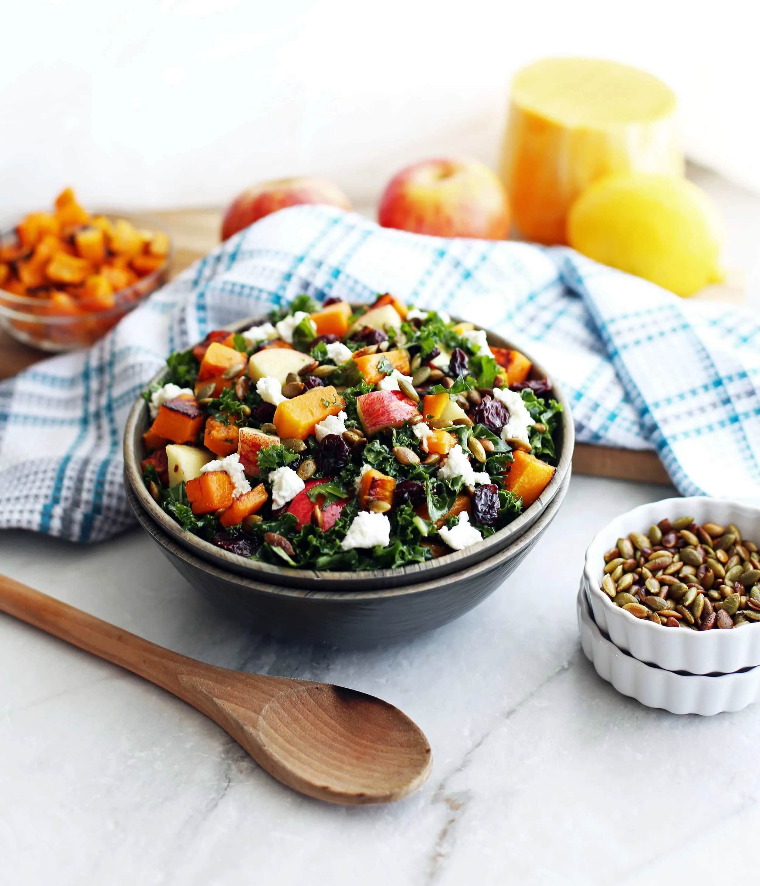 A wooden bowl filled with Roasted Butternut Squash and Apple Kale Salad with Lemon Vinaigrette