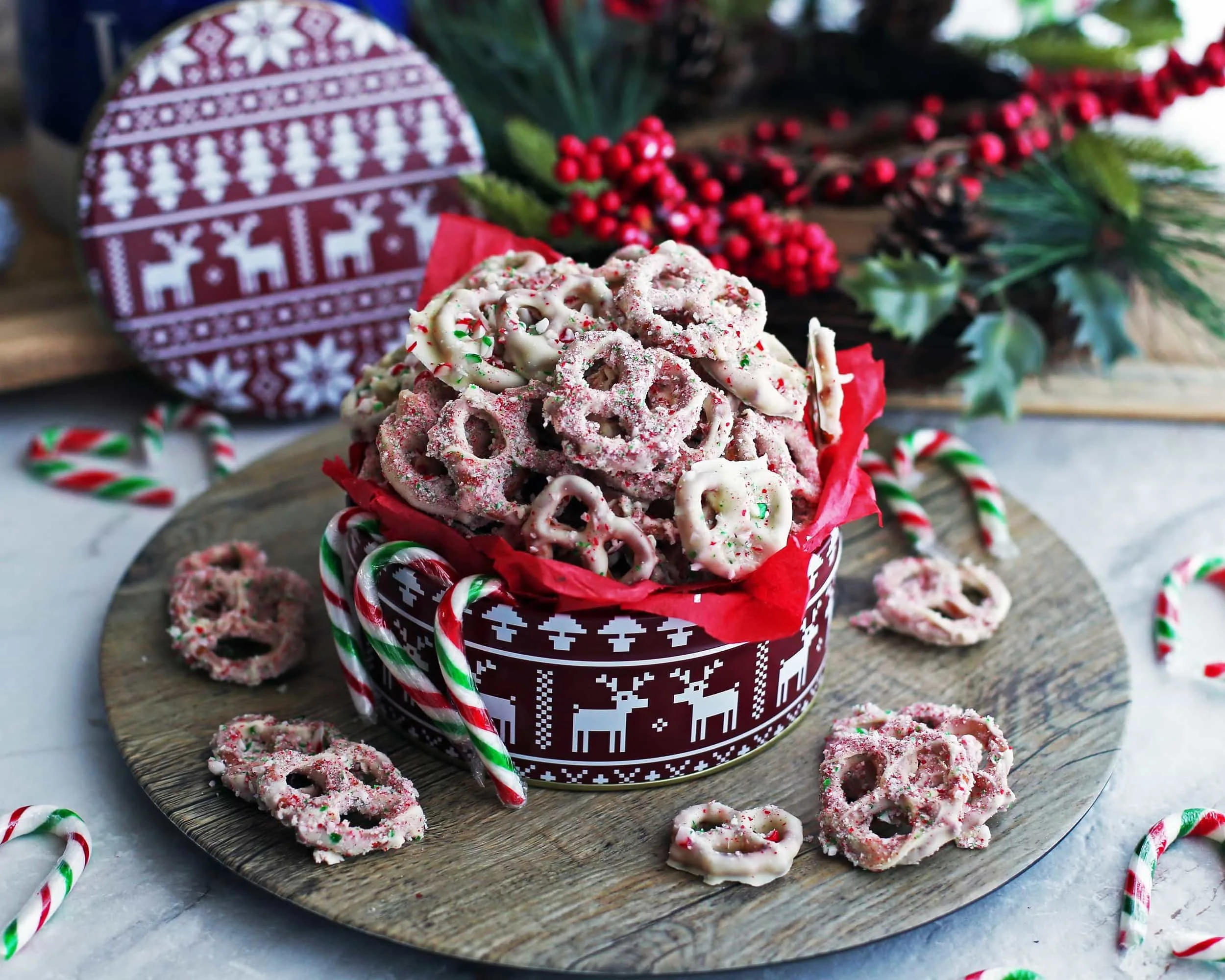 Four-ingredient candy cane chocolate-covered pretzels overflowing in a large red tin.