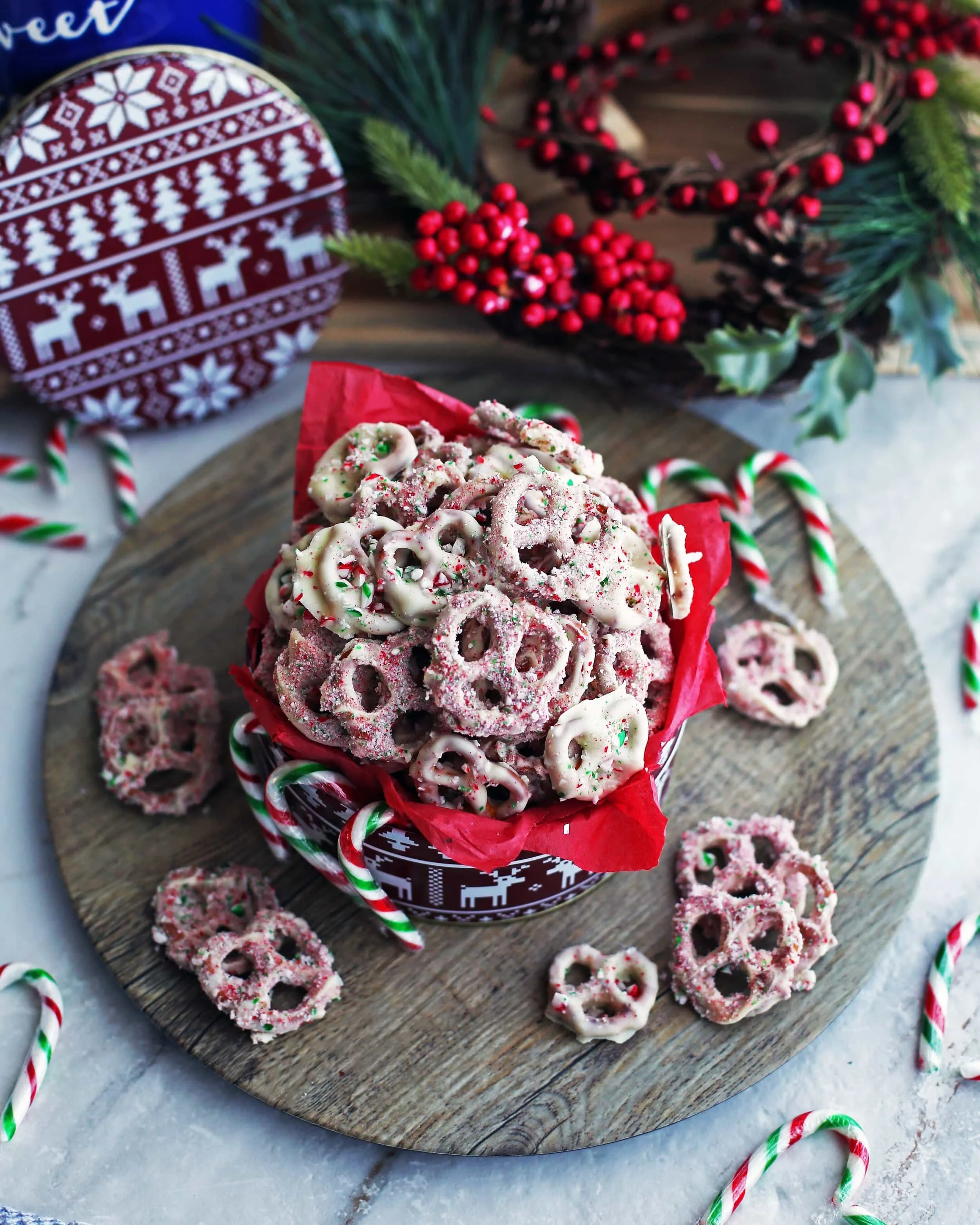 Side angled shot of candy cane chocolate-covered pretzels in a red tin container.