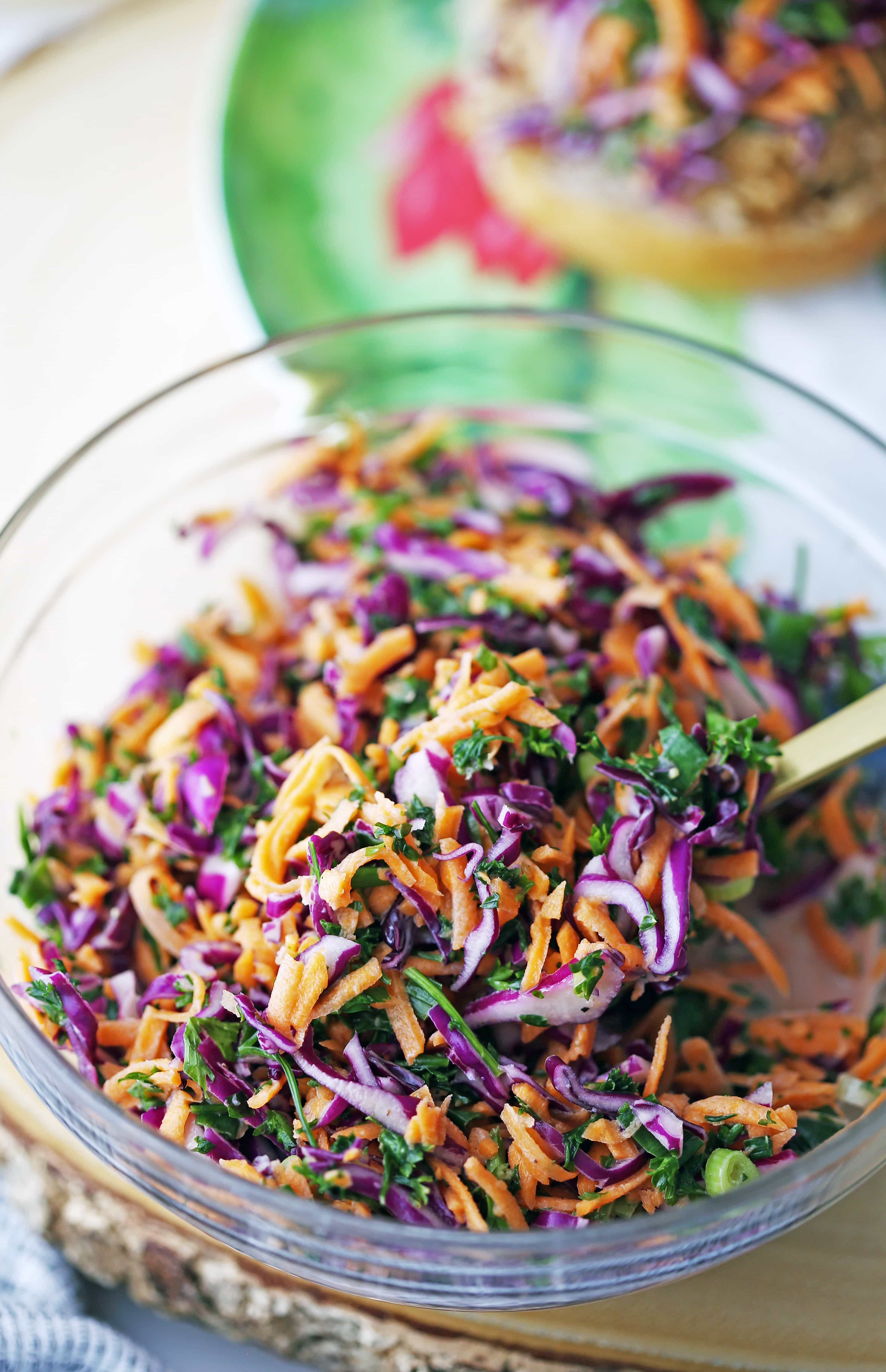 Colourful carrot cabbage coleslaw with apple cider vinegar dressing in a glass bowl.