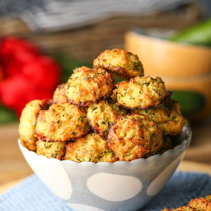 Golden-brown baked cheesy zucchini bites in a white and blue bowl.
