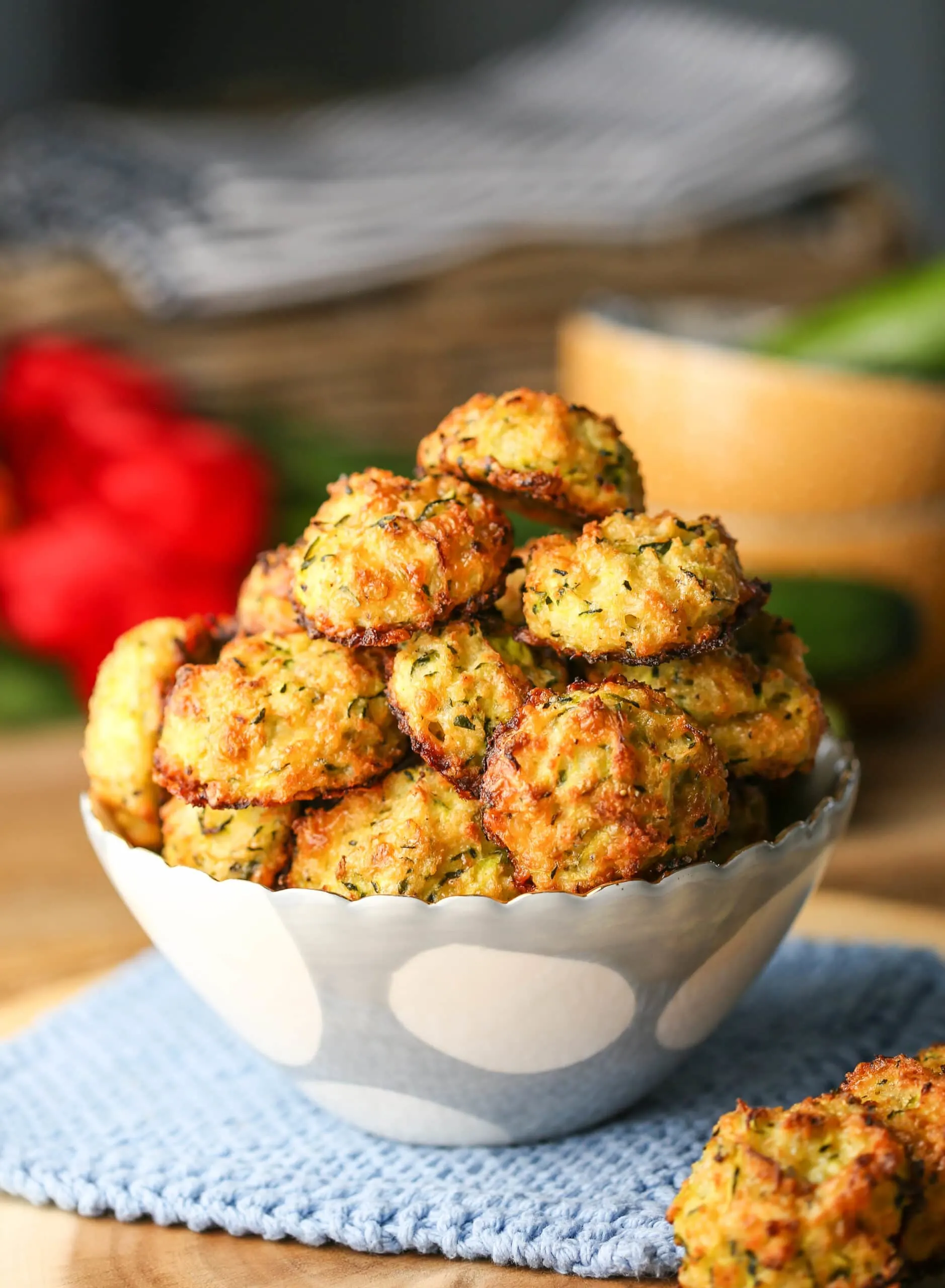 Golden-brown baked cheesy zucchini bites in a white and blue bowl.