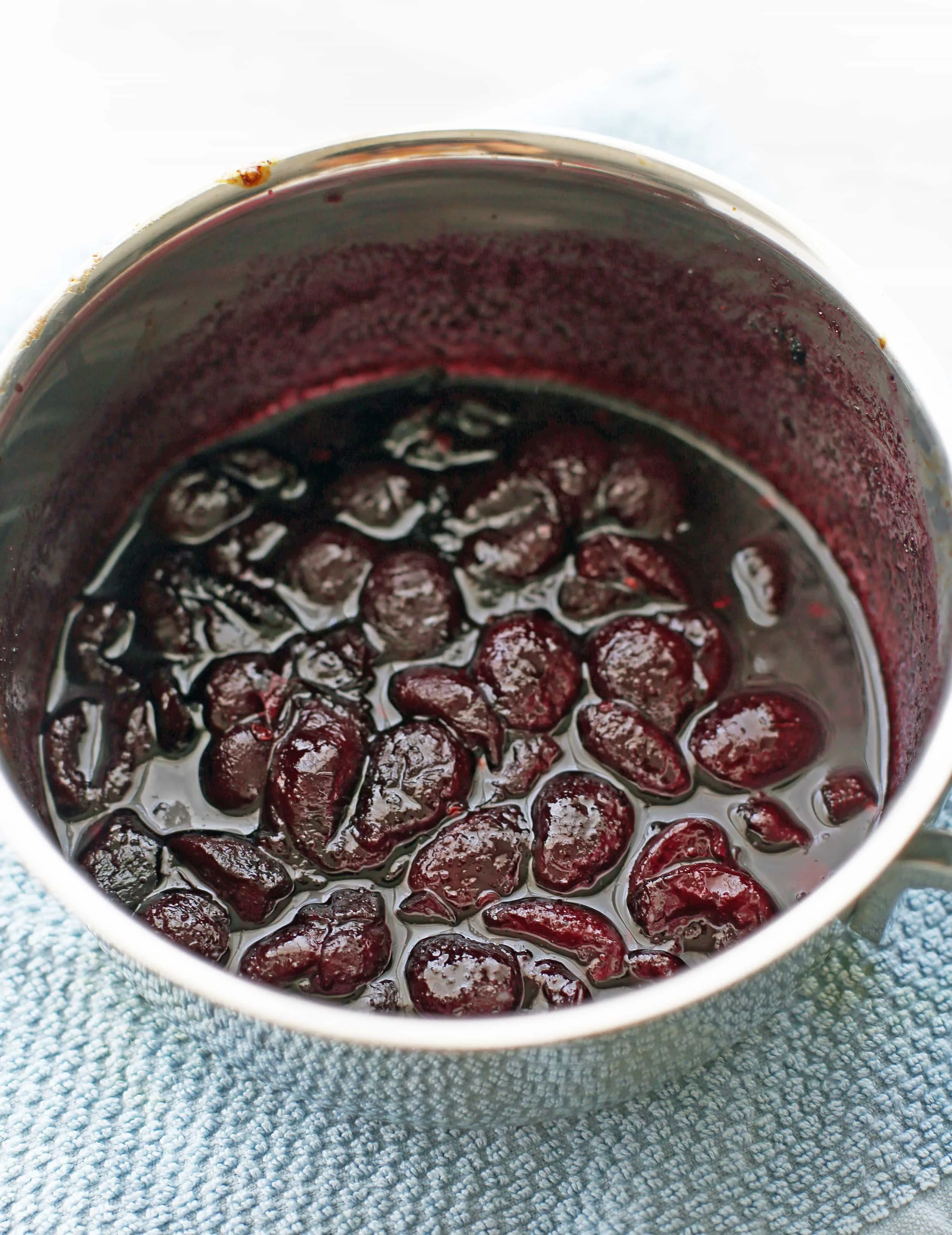 Cooked down cherries with chipotle peppers, brown sugar, garlic powder, and apple cider vinegar in a saucepan.