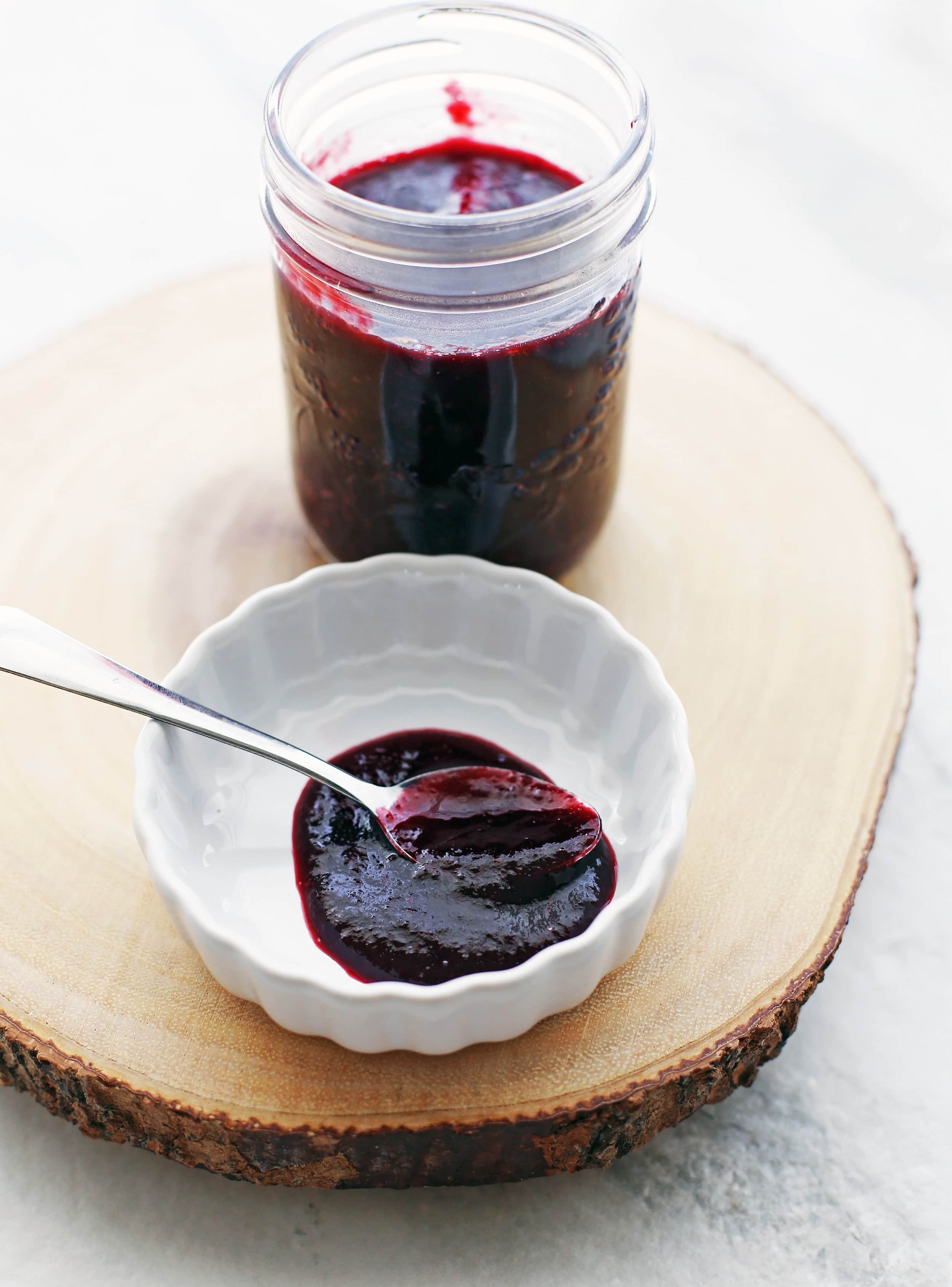 A spoonful of cherry chipotle sauce in a small white bowl and in a small mason jar.
