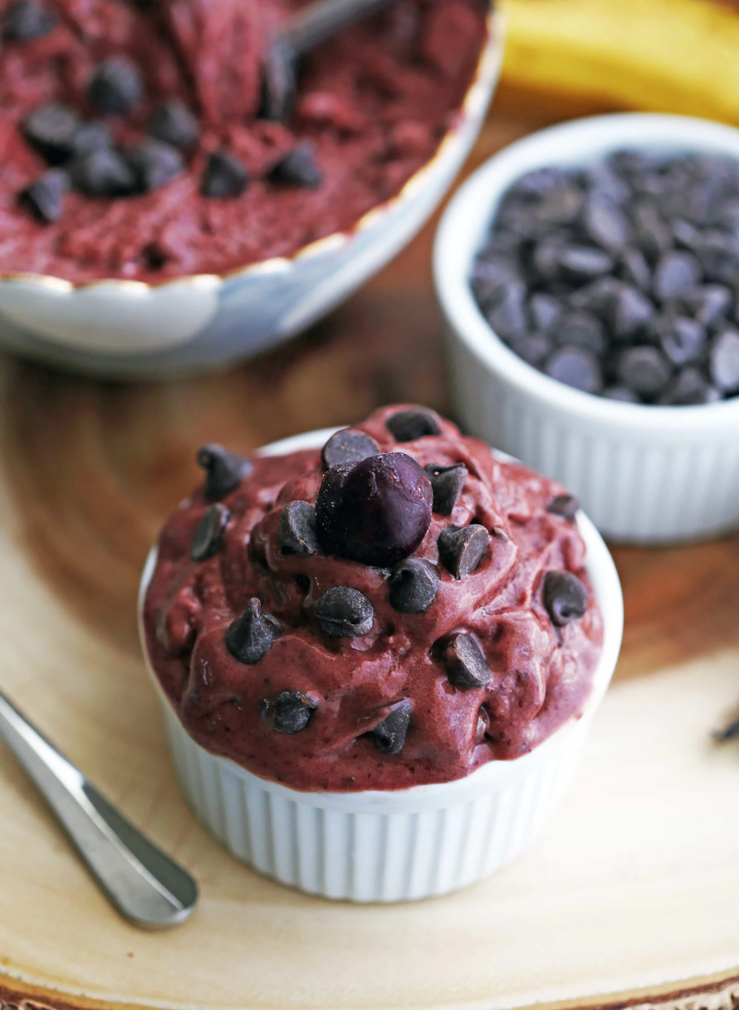 A small white bowl of cherry chocolate frozen yogurt with chocolate chips and a cherry on top.