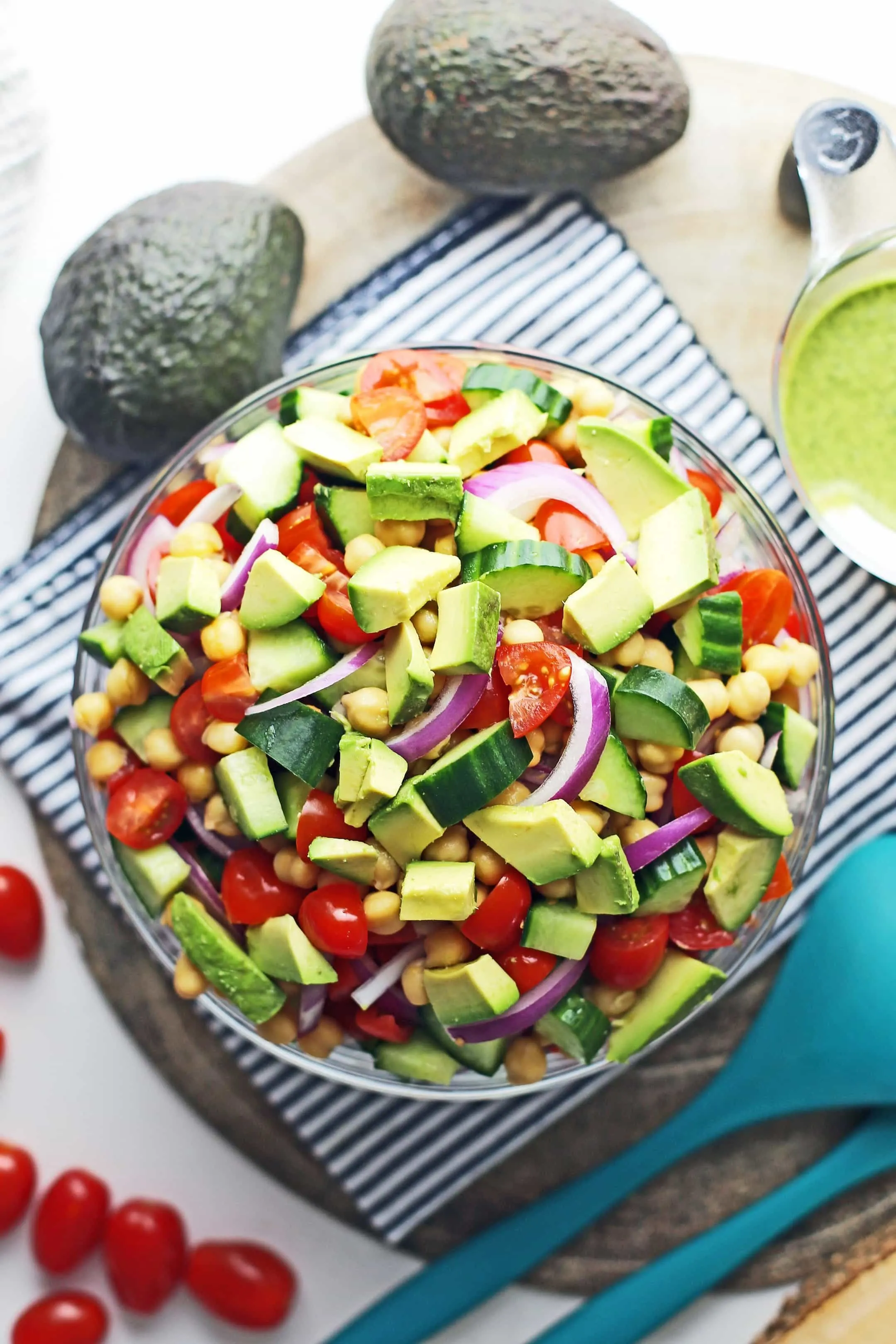 Overhead view of cooked chickpeas and chopped and sliced cucumber, avocado, tomatoes, and red onions.