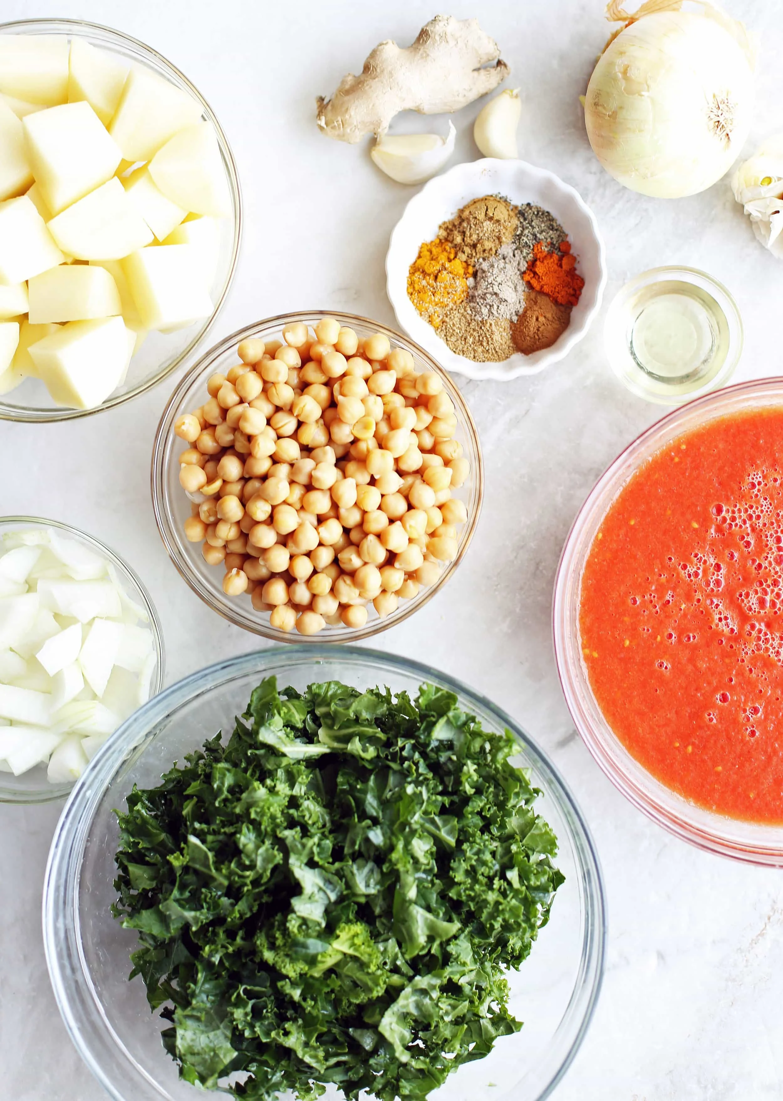 Bowls of kale, chickpeas, potatoes,onions, pureed tomatoes, spices, garlic, and onion.