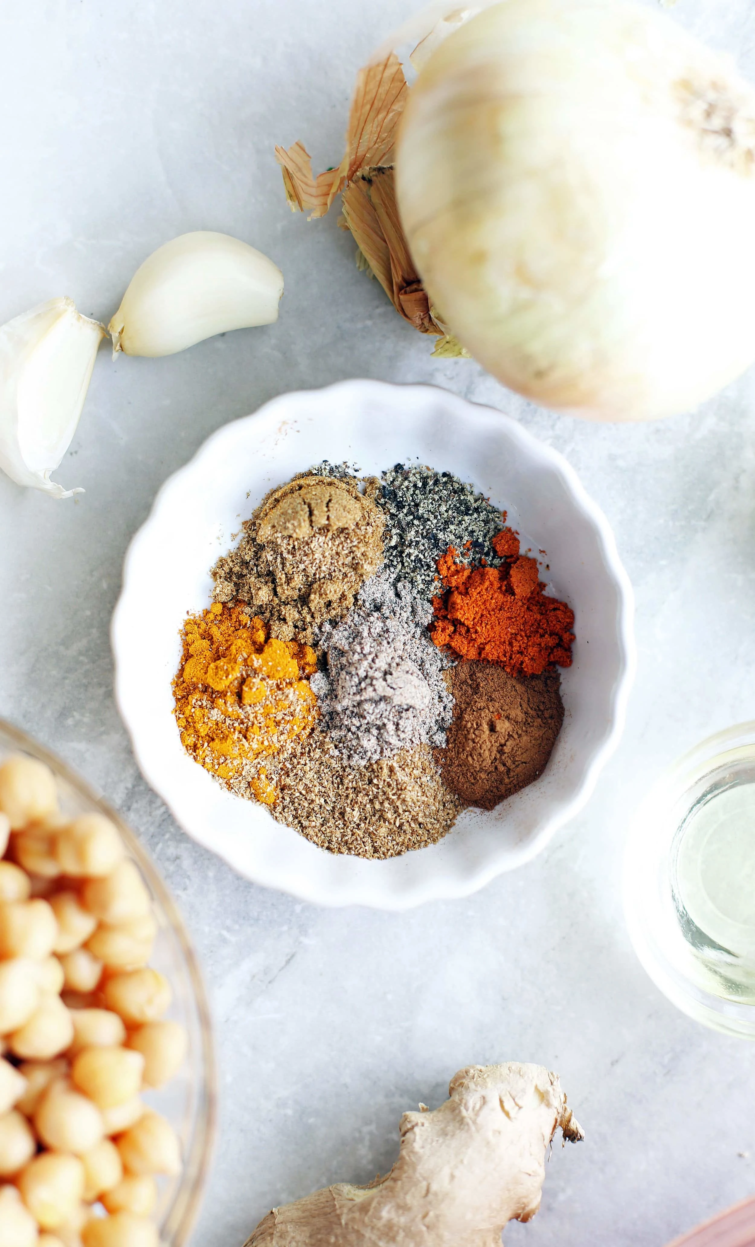 An overhead view of a bowl of spices that includes turmeric, cumin, coriander, cinnamon, cayenne pepper, and black pepper.