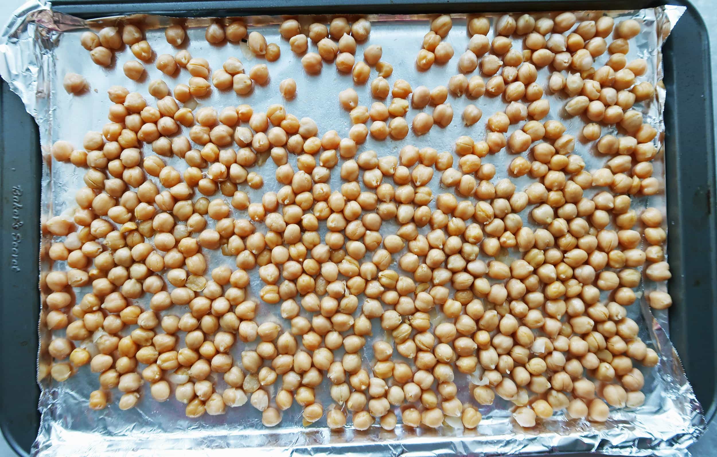 A baking sheet covered in chickpeas.