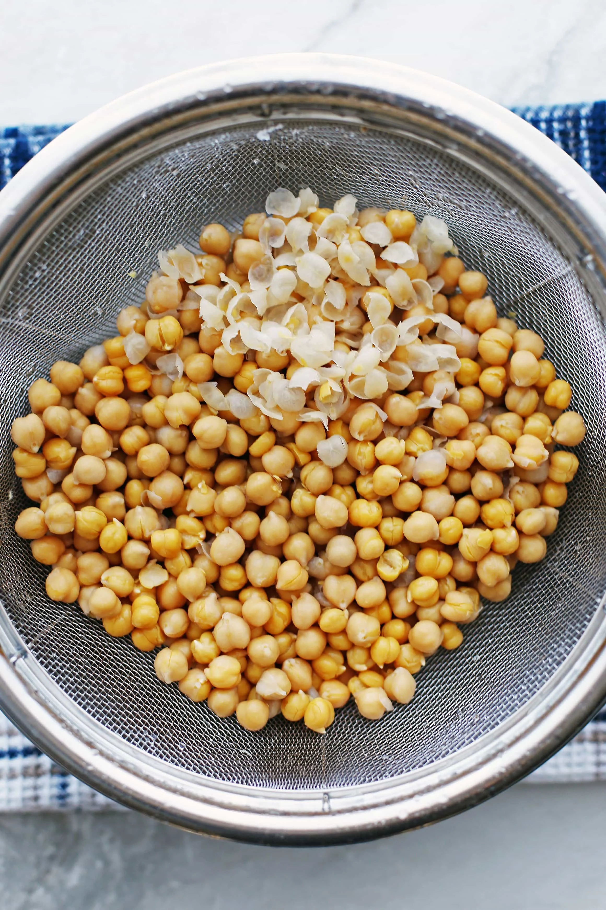 Rinsed and drained cooked chickpeas in a wire strainer.