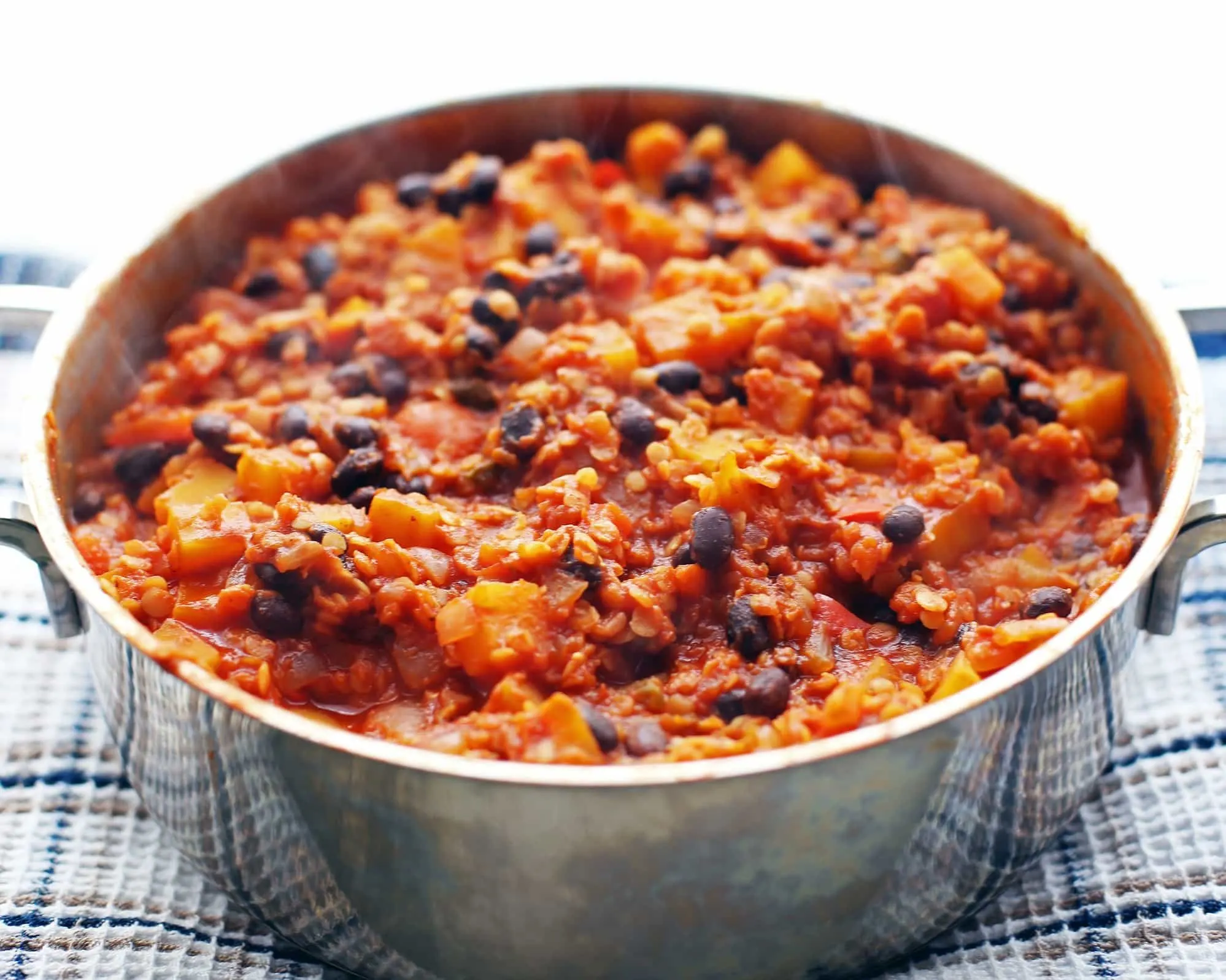 Red lentil and butternut squash chili in a large metal pot.