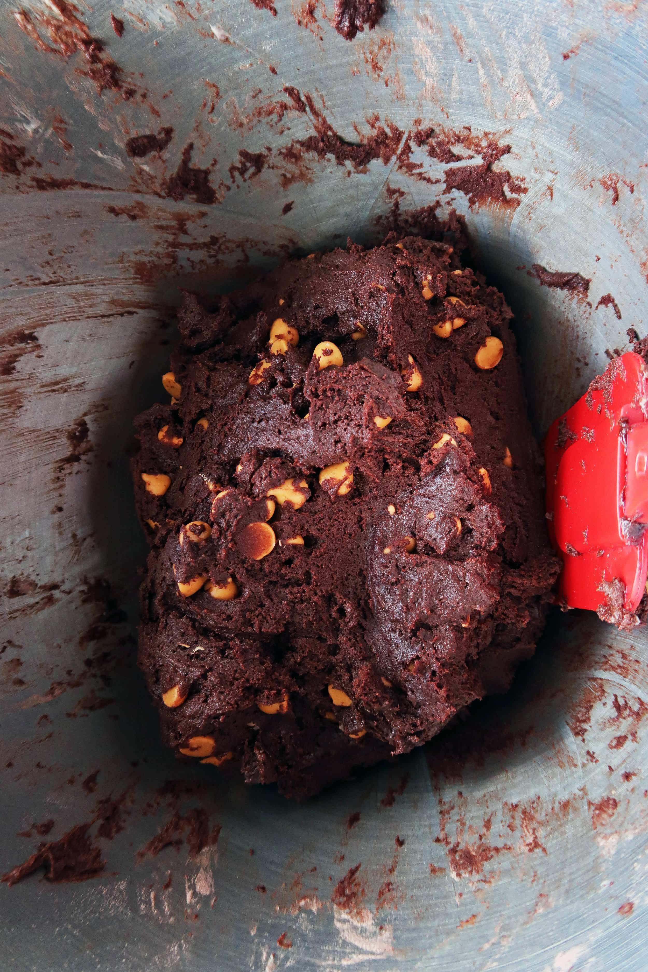 Chocolate butterscotch chip cookie dough in a large metal bowl.