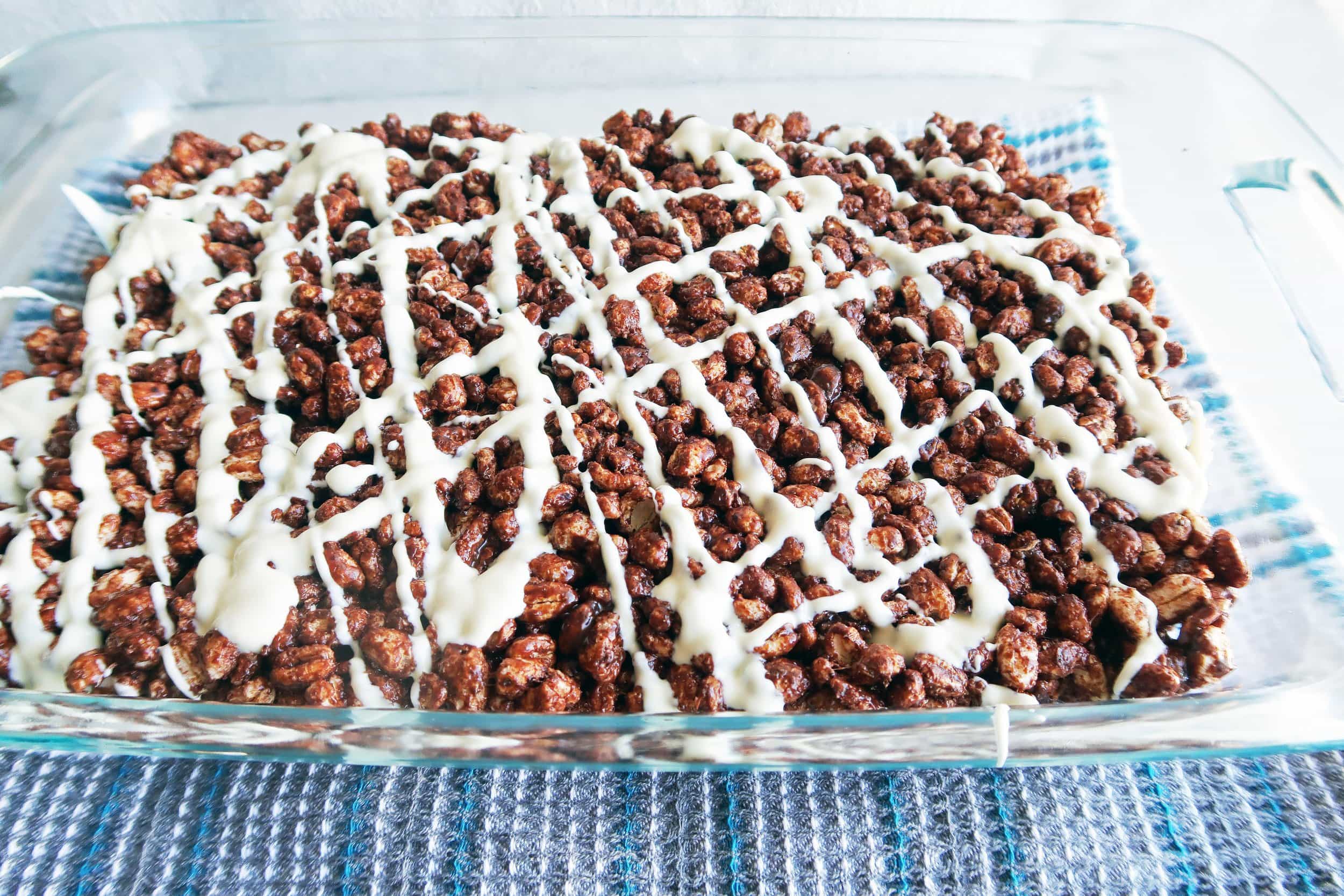 Chocolate Marshmallow Puffed Wheat Squares with white chocolate drizzle in a large glass baking dish.