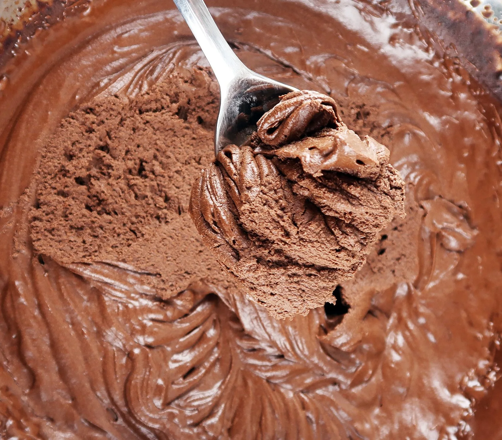 A spoon digging into chocolate mousse.