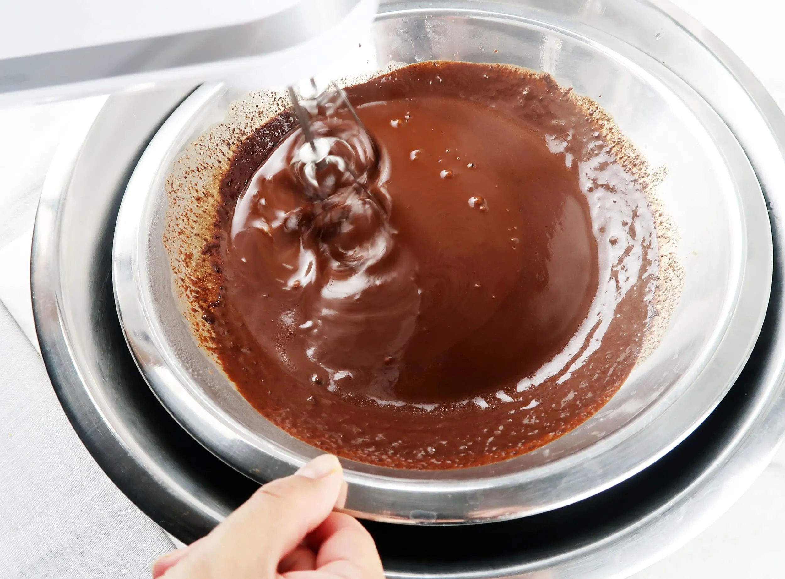 Melted dark chocolate in a bowl surrounded by an ice bath.