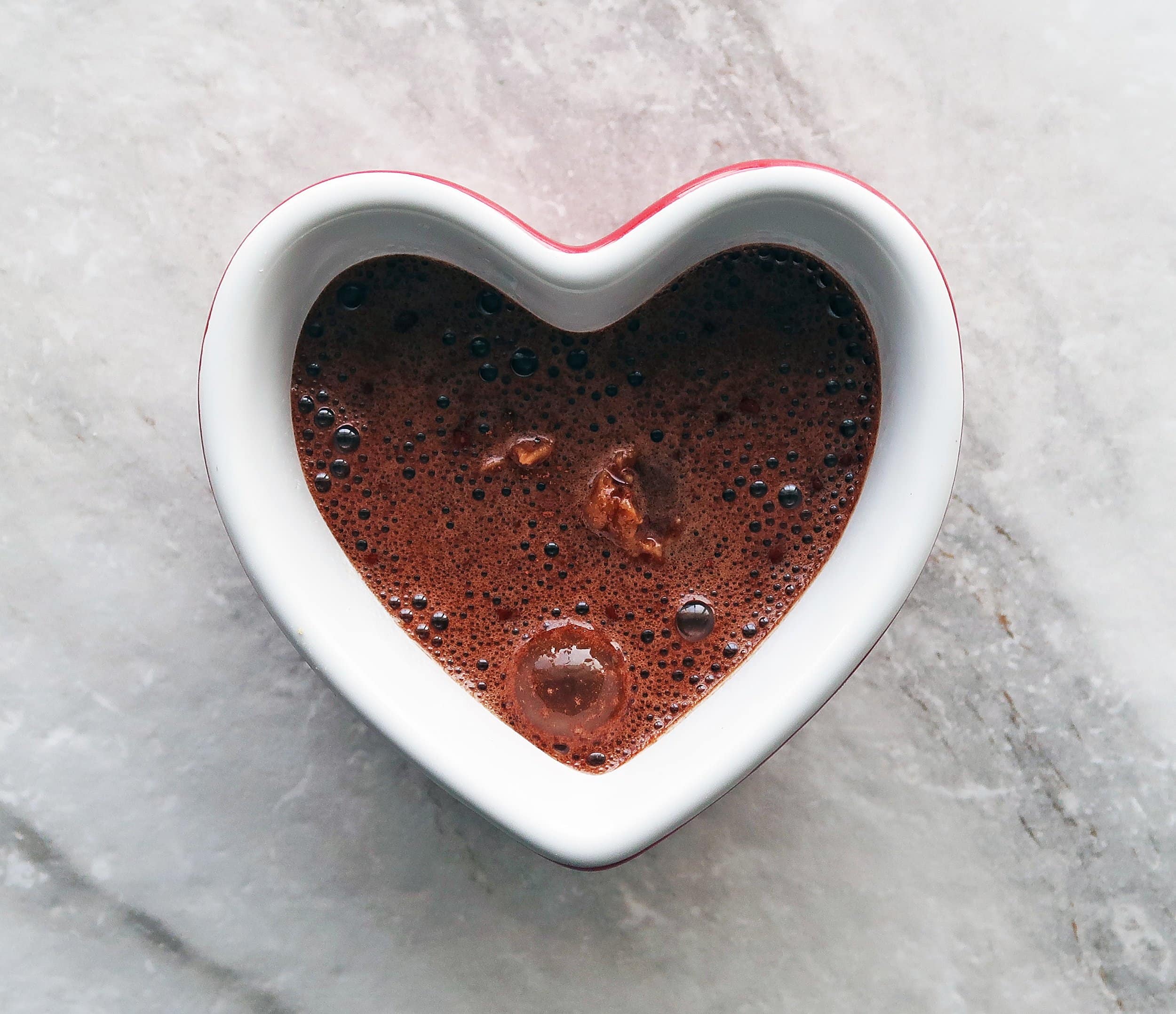 Chocolate cake batter in a heart-shaped ramekin.