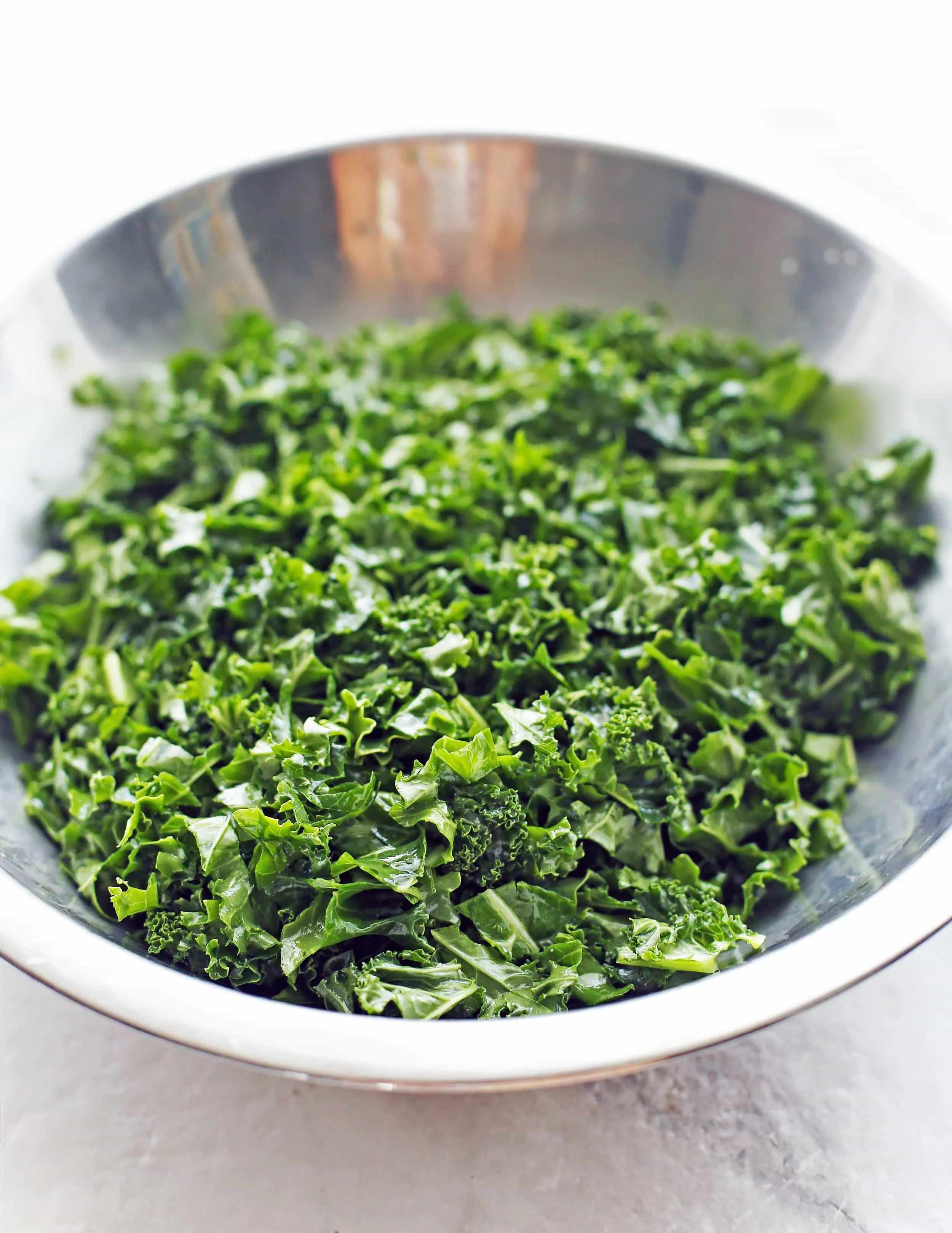 Chopped green curly kale in a metal bowl.