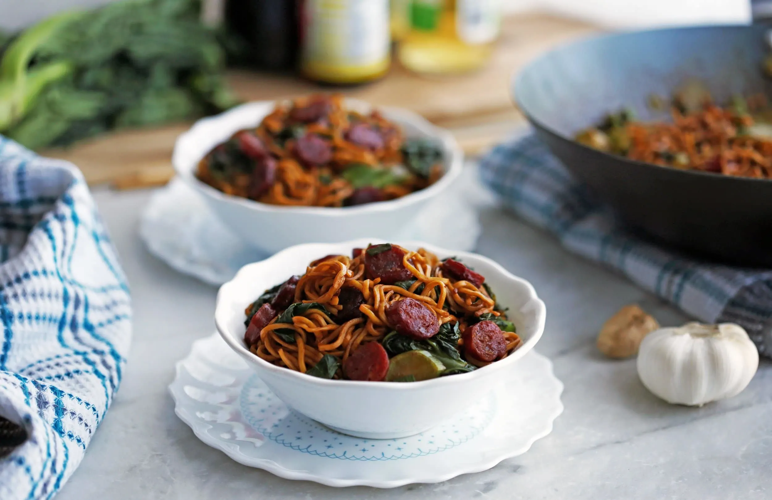 Two bowls of Lo mein noodles with Chinese sausage (lap cheong) and gai lan (Chinese broccoli).