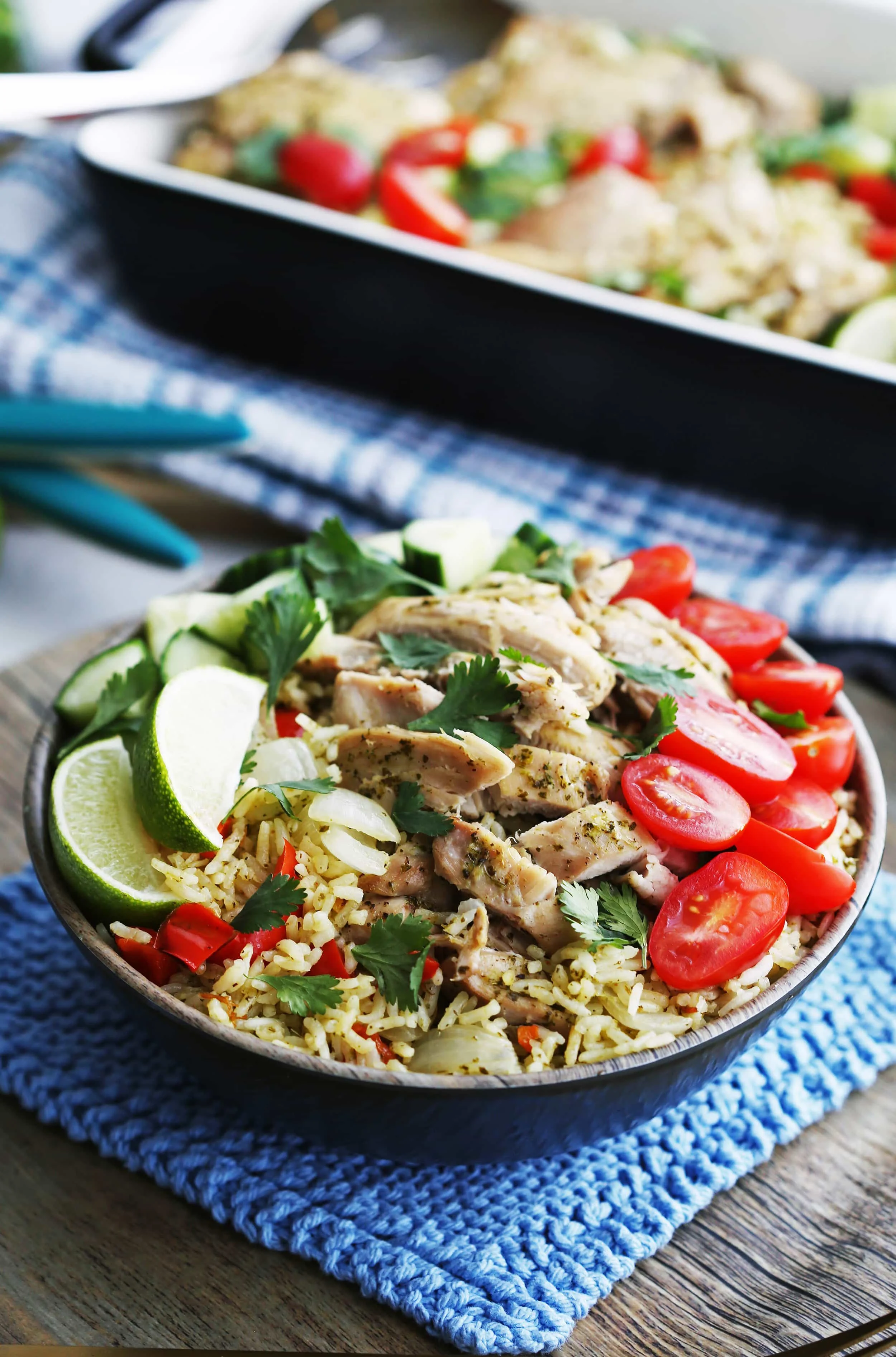 A full bowl of Instant Pot Cilantro Lime Chicken and Rice with fresh tomatoes, cilantro, cucumber, and lime wedges.