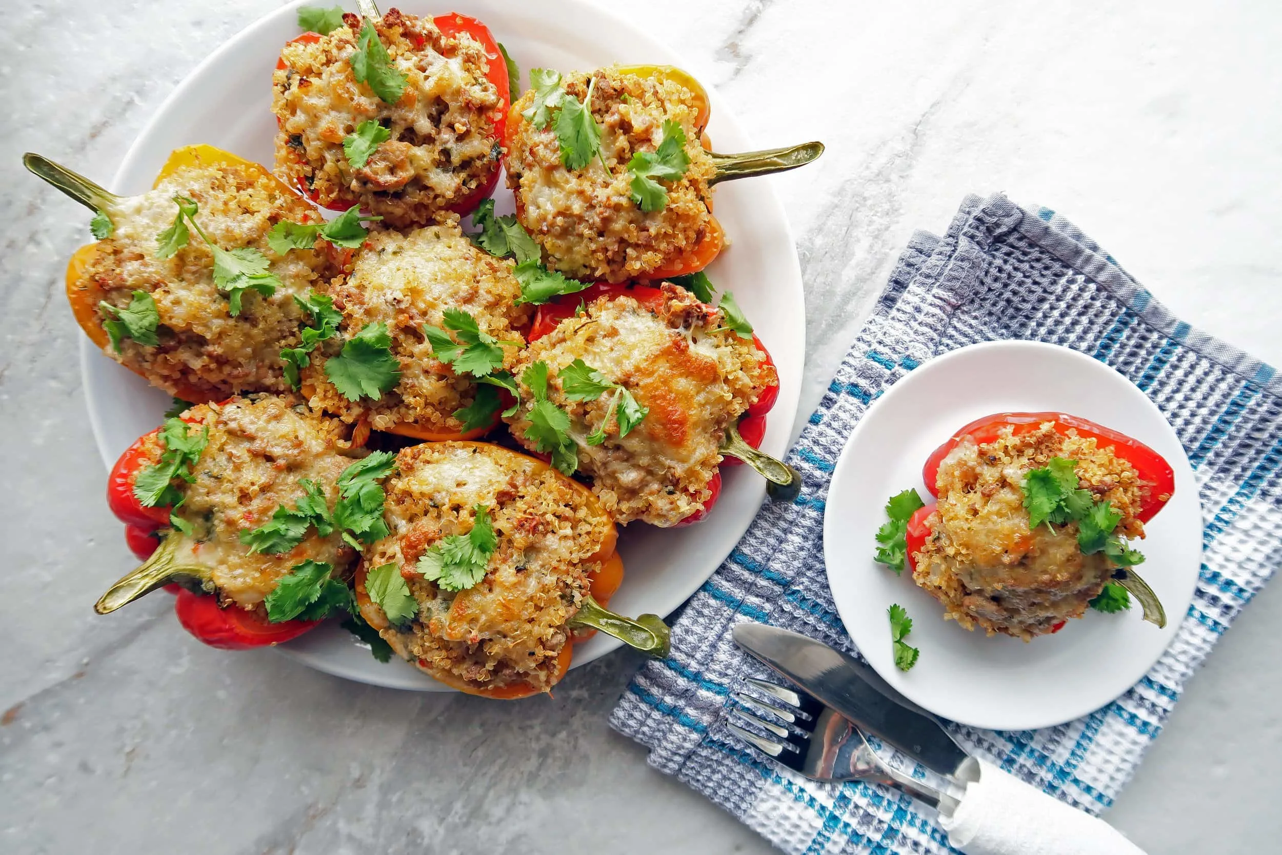 One large and one small plate of Cilantro Lime Turkey Quinoa Stuffed Bell Peppers with cilantro on top.