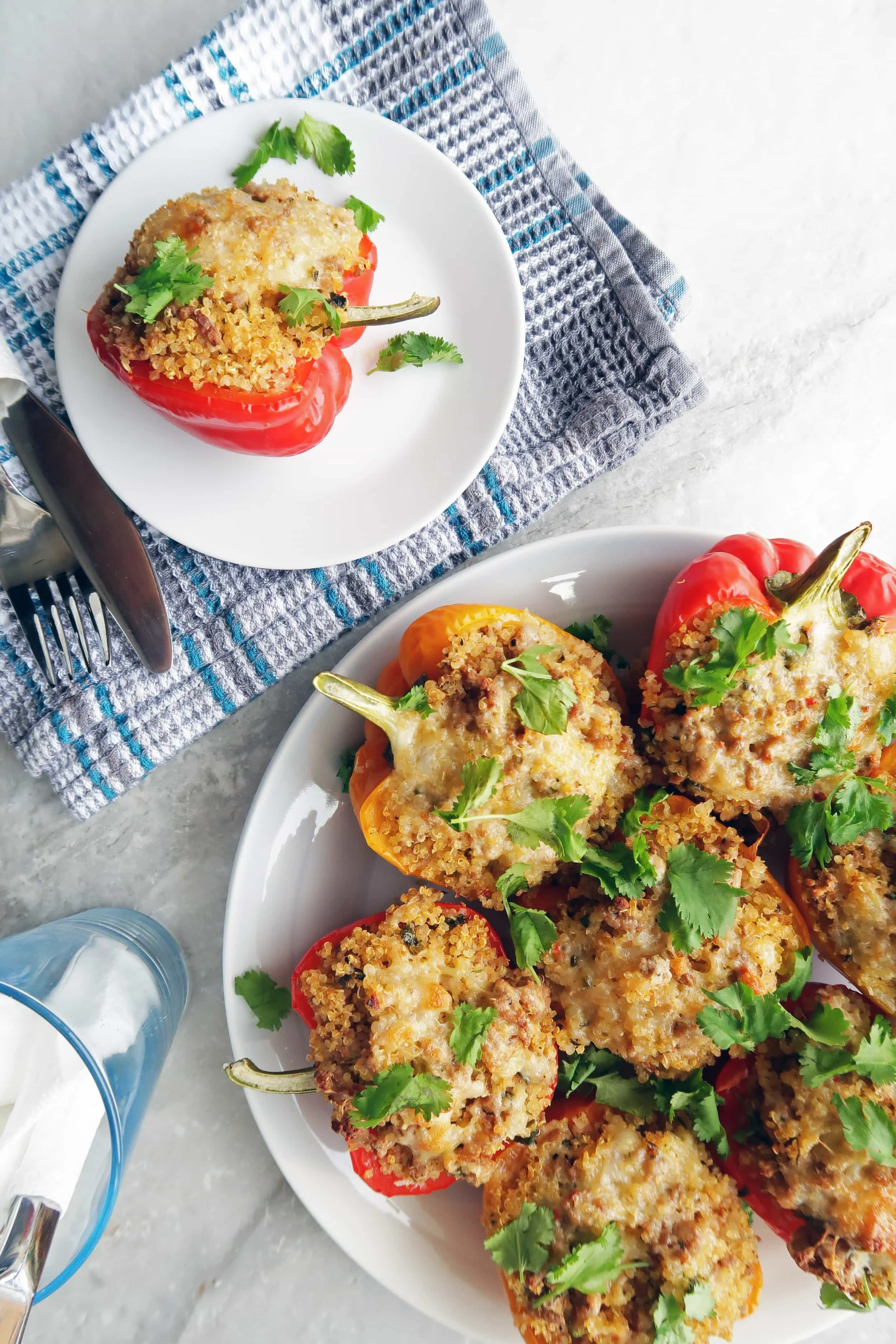 Two plates of Cilantro Lime Turkey Quinoa Stuffed Peppers topped with cilantro.