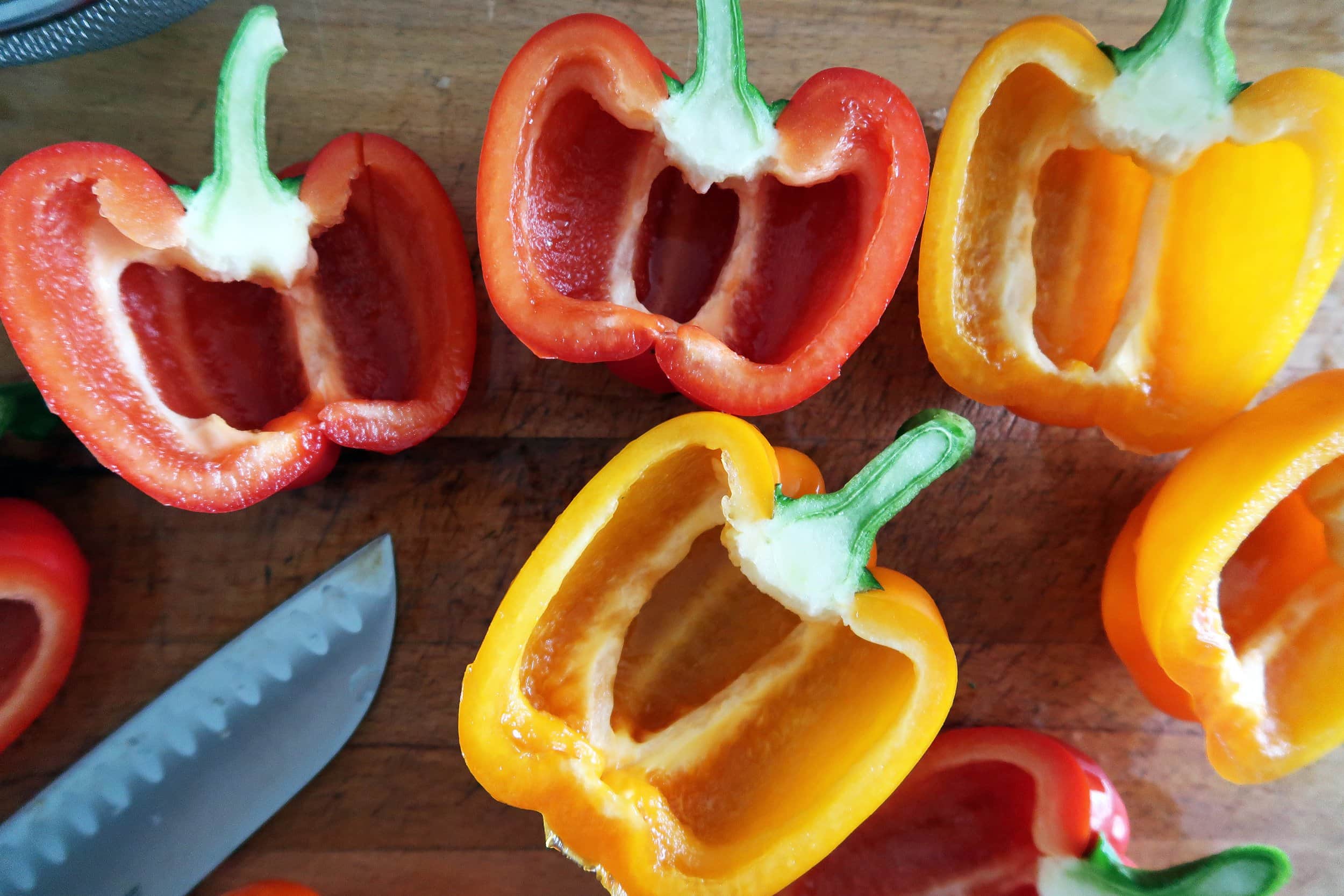 The vibrant interior of red and orange bell peppers, sliced in half with the seed removed.