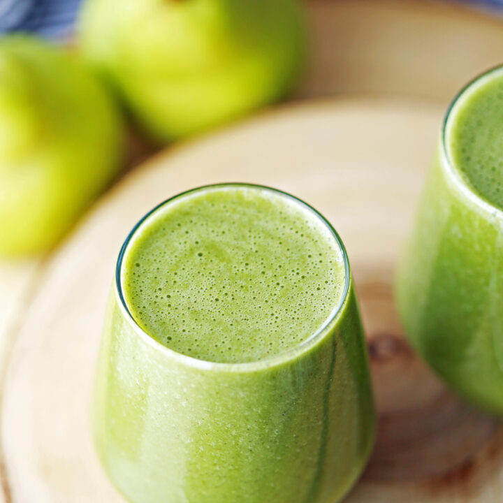 A top angled view of a glass filled with cinnamon pear green smoothie with spinach.