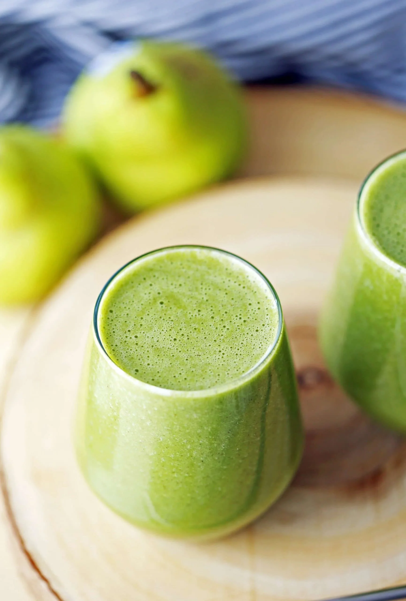 A top angled view of a glass filled with cinnamon pear green smoothie with spinach.