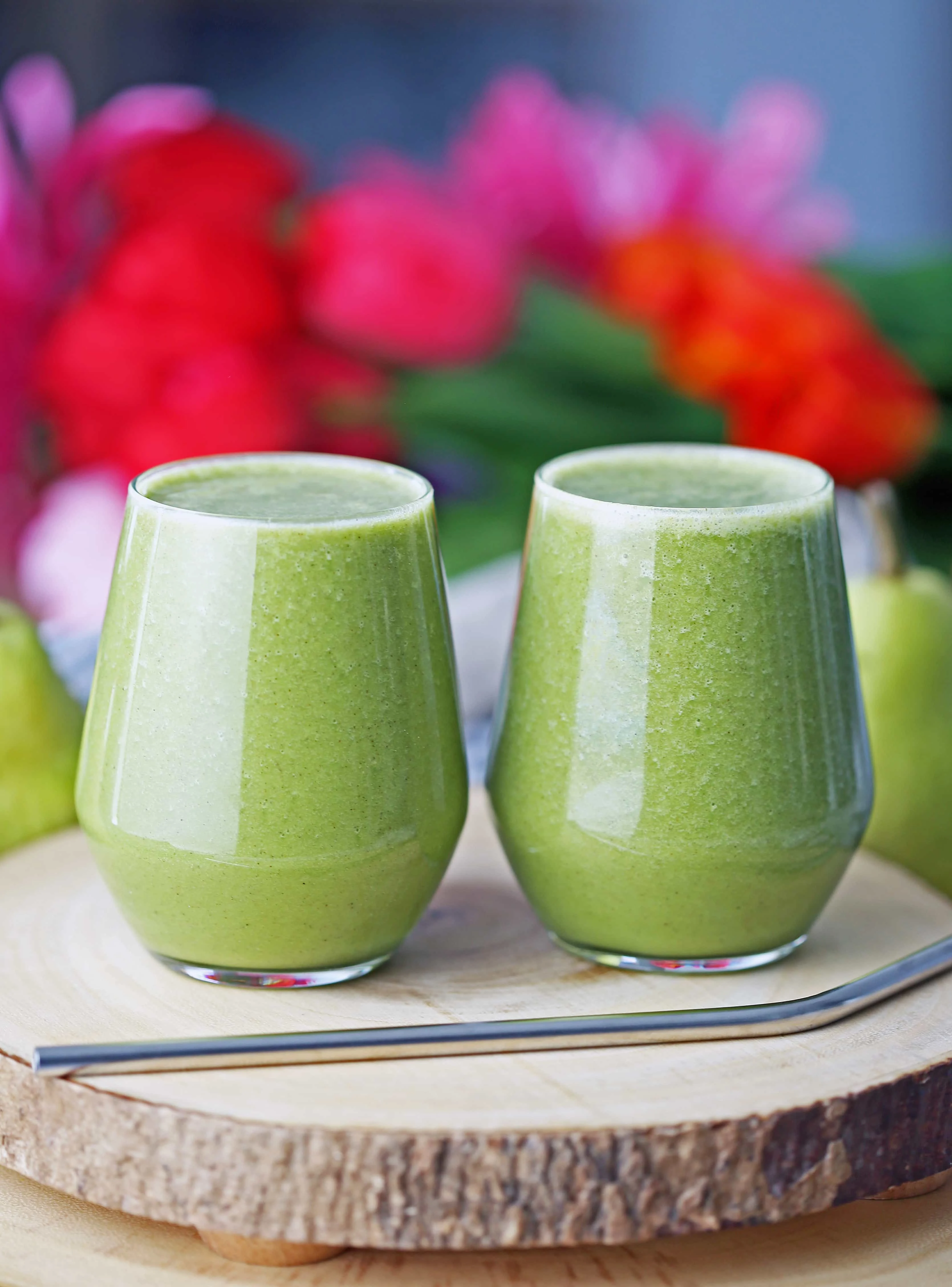 Cinnamon pear green smoothie in two glasses side by side on a wooden board.