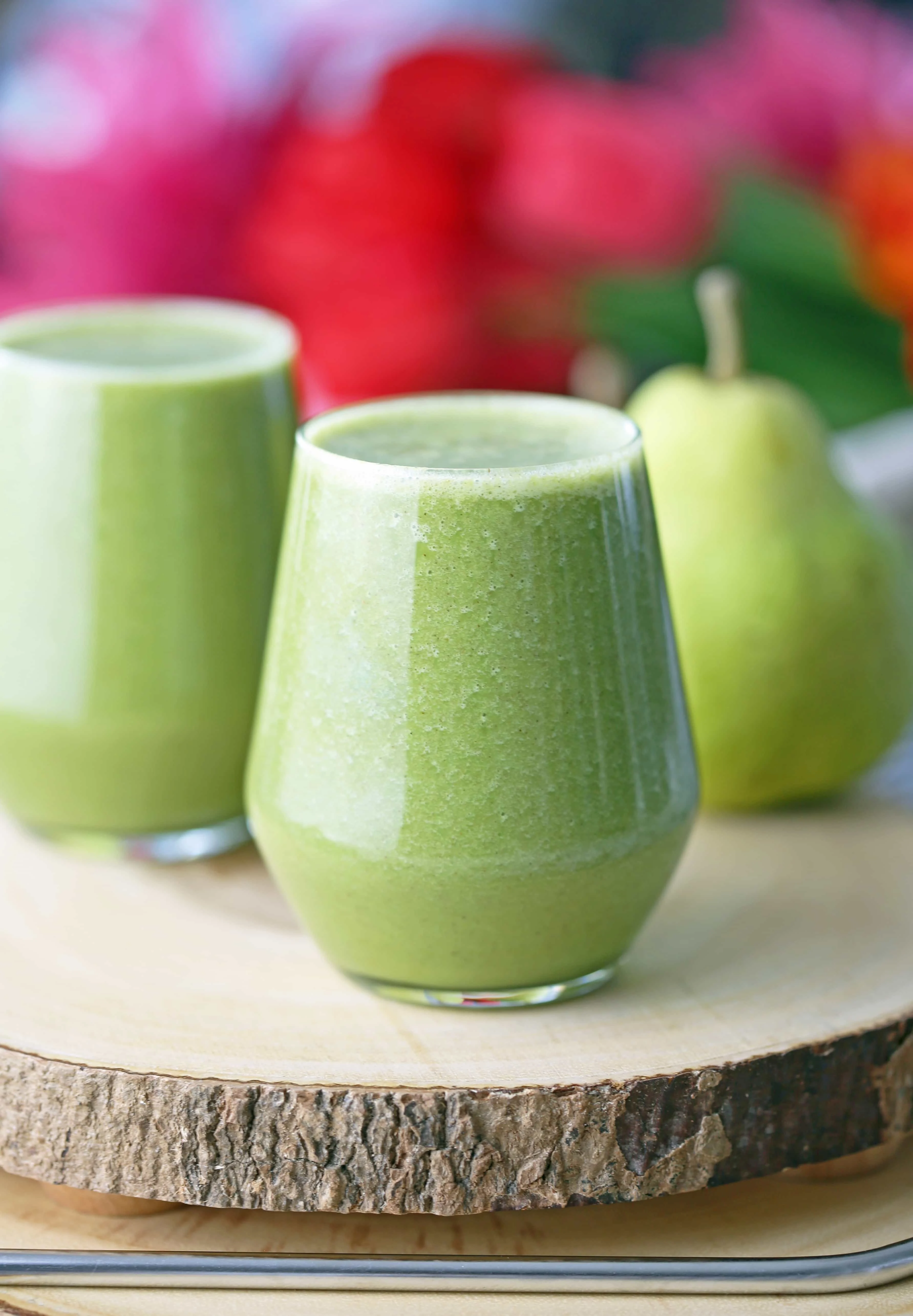 A side view of two glasses filled with cinnamon pear smoothie on wooden board.