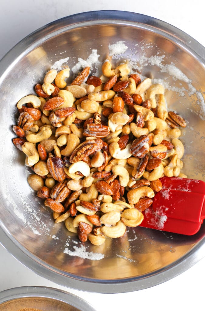 Mixed nuts folded with beaten egg whites in a stainless steel bowl.