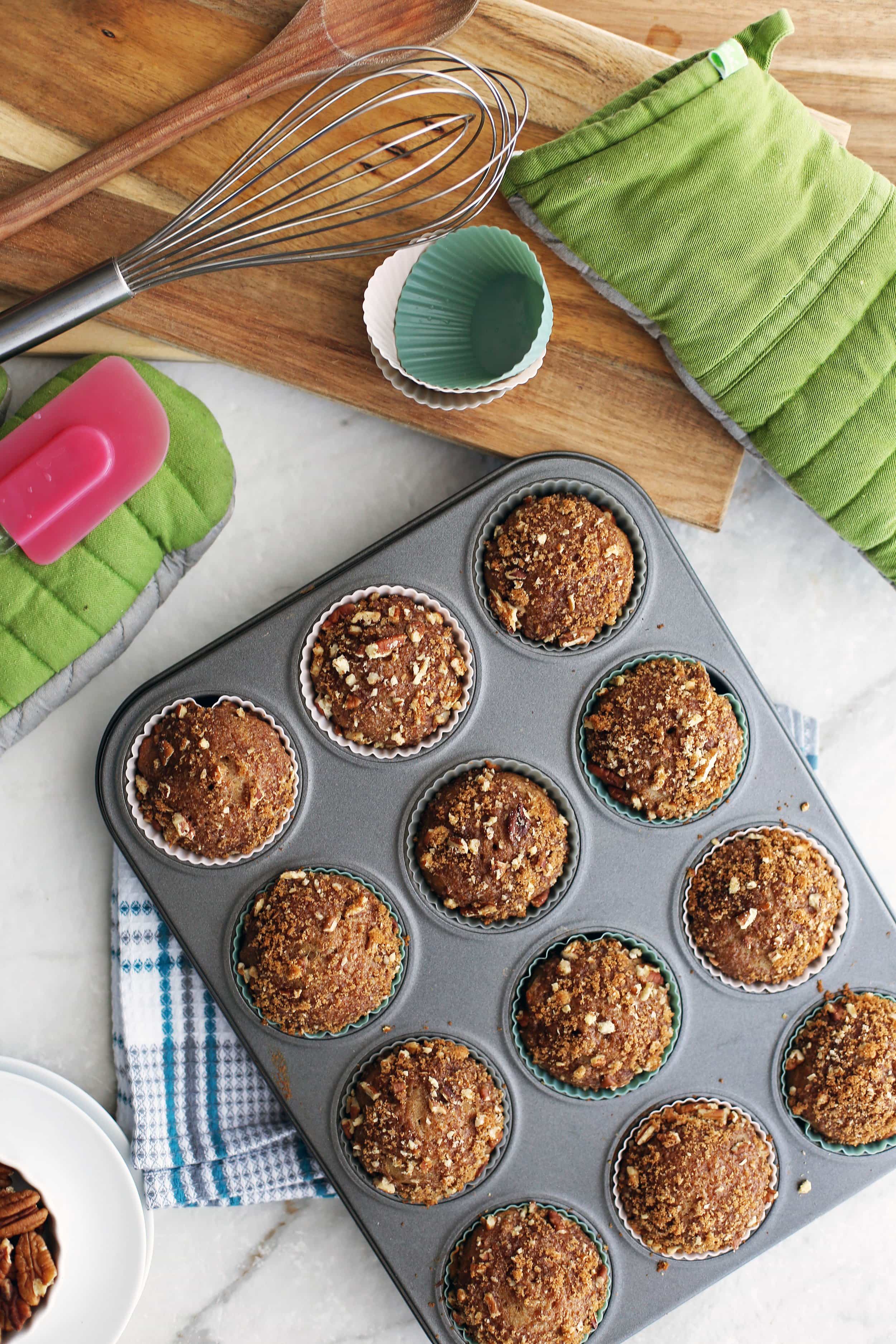 Overhead view of a dozen cinnamon pecan applesauce muffins in a muffin pan.