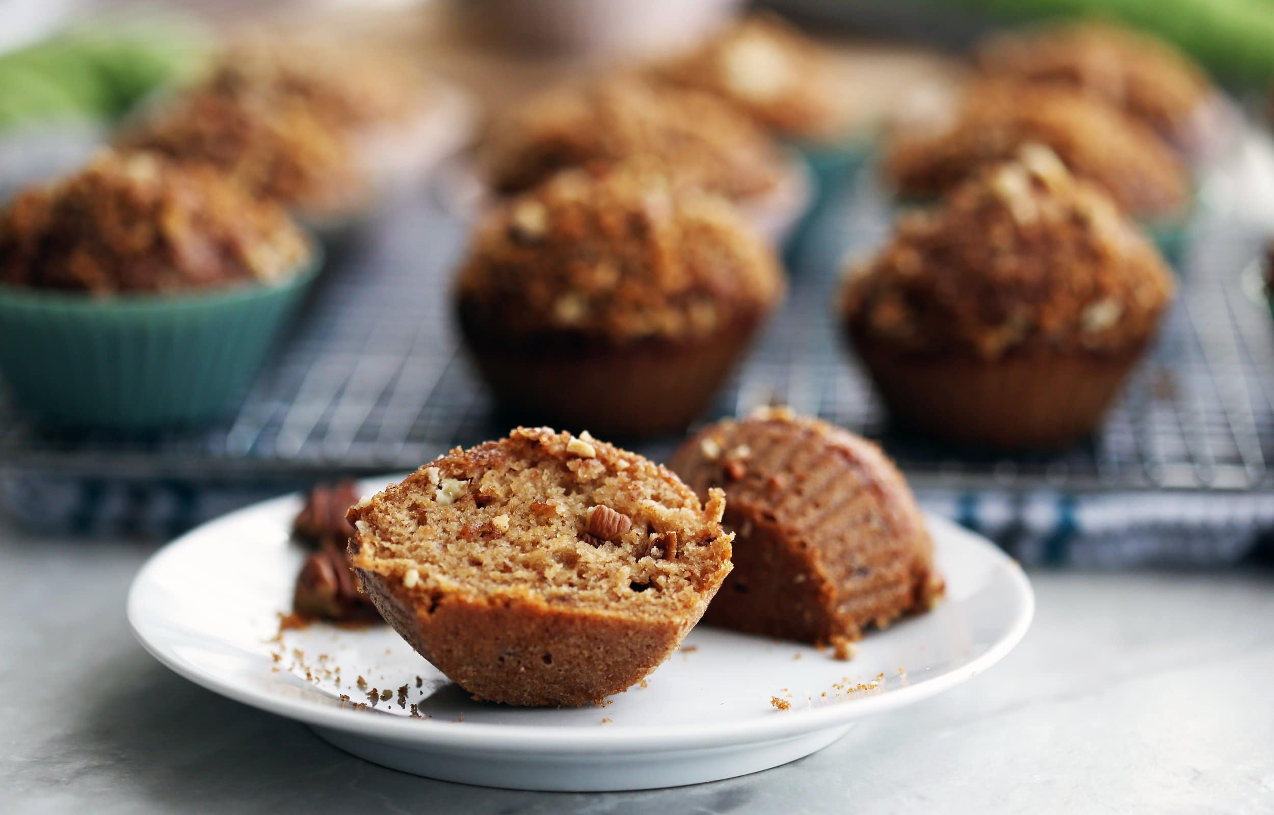 A cinnamon pecan applesauce muffin cut in half on a white plate.