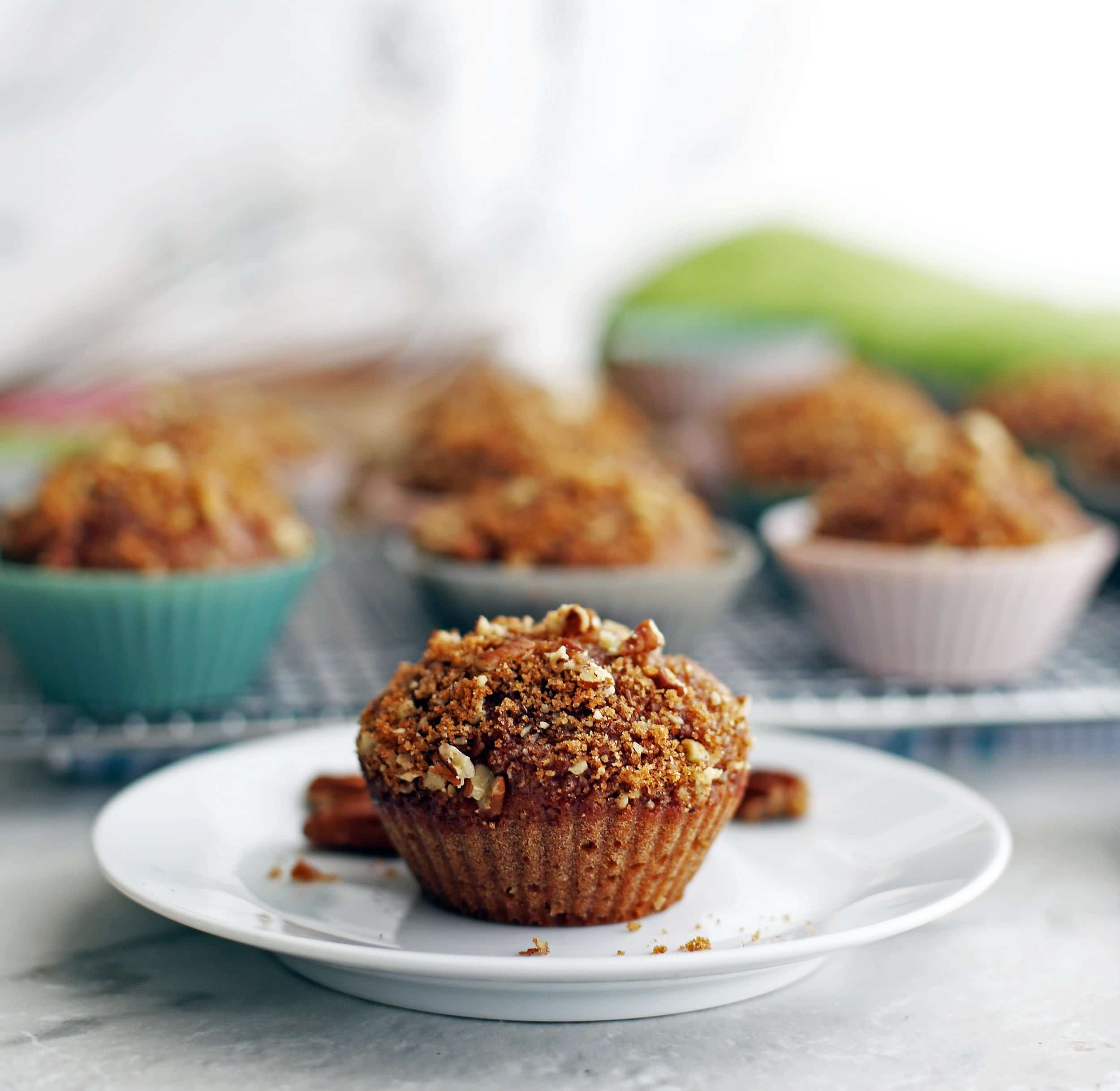 Side view of a cinnamon pecan applesauce muffin on a white plate.