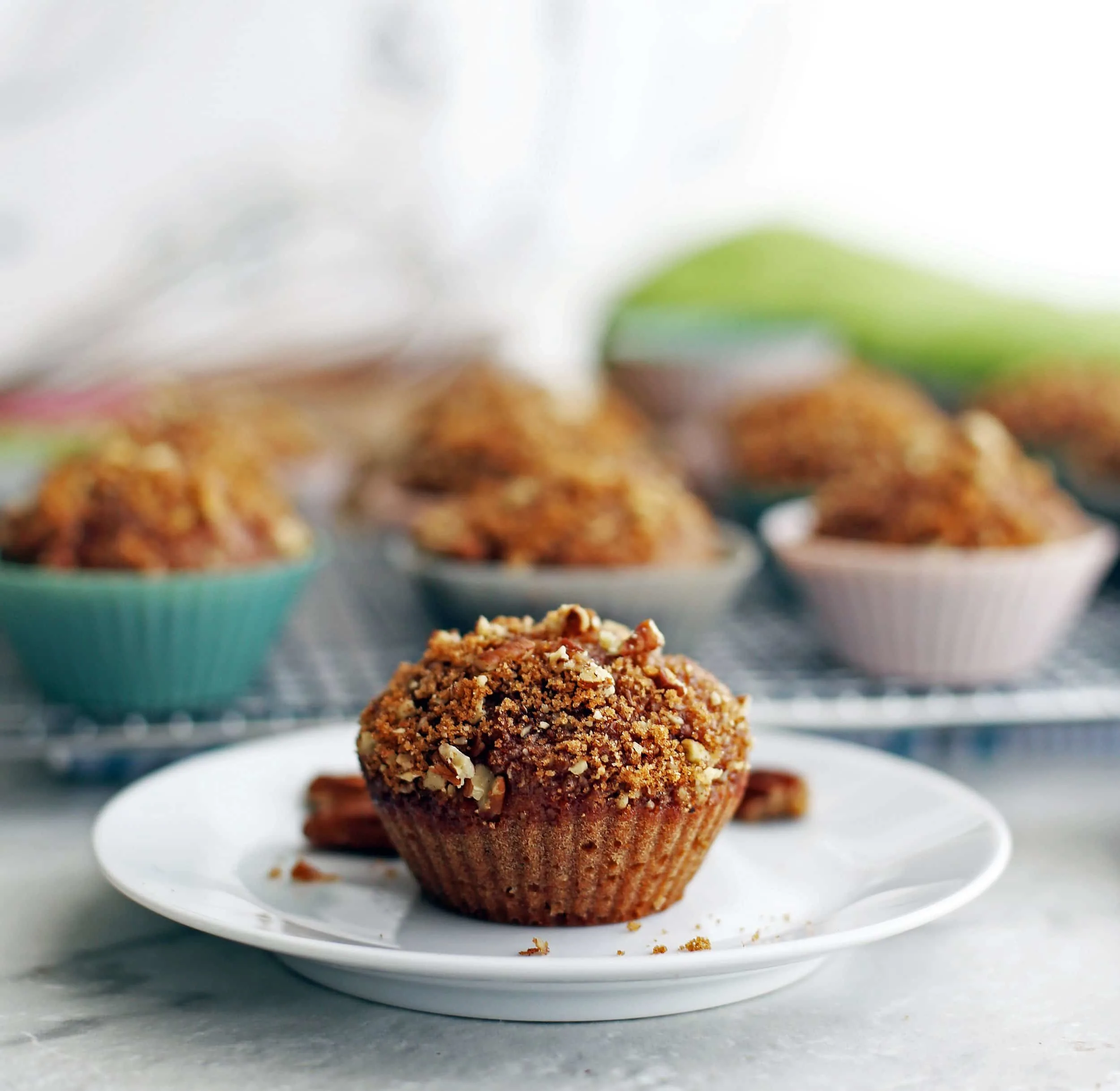 Side view of a cinnamon pecan applesauce muffin on a white plate.