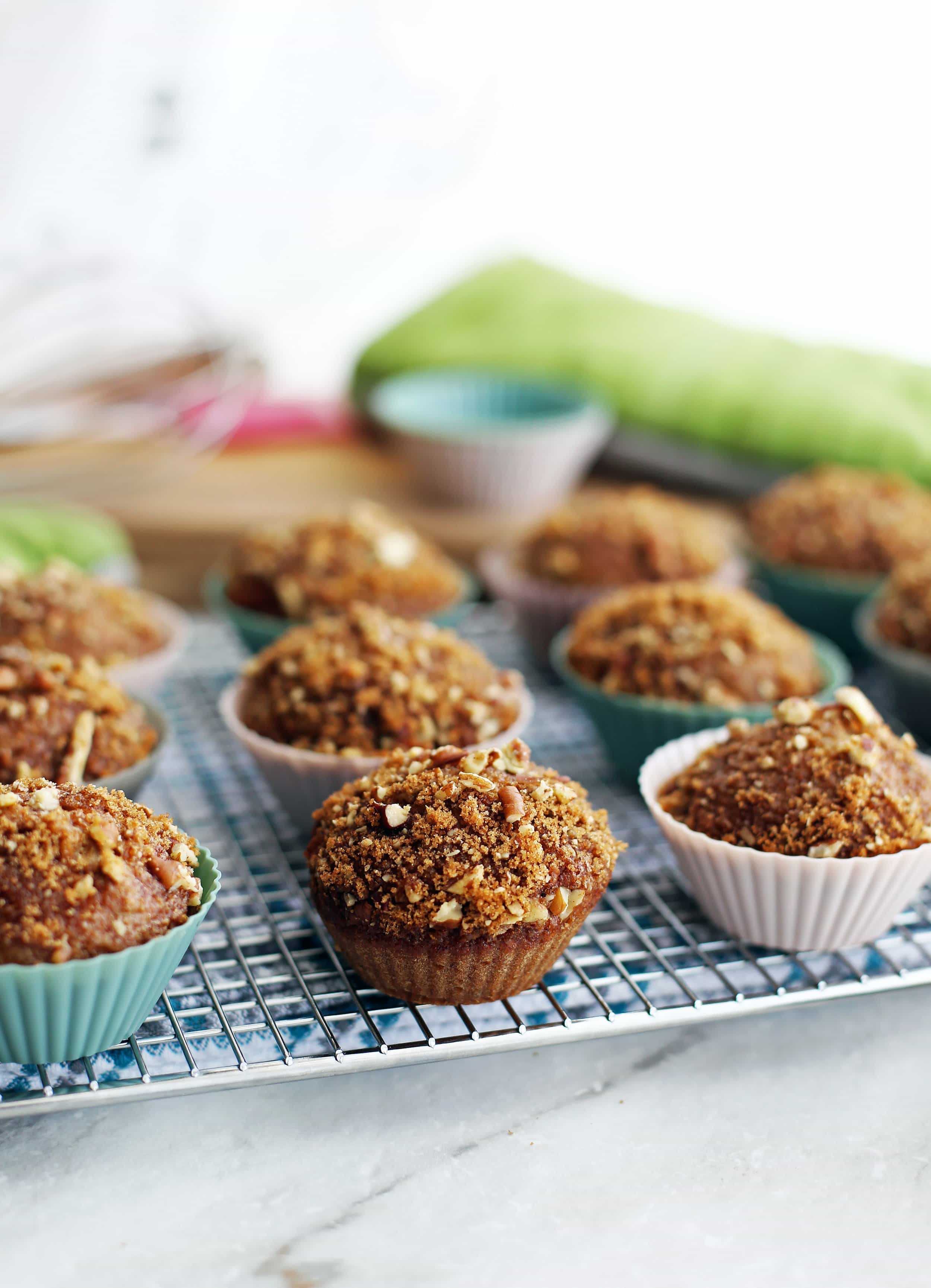 Side view of cinnamon pecan applesauce muffins with a crunchy pecan topping on a cooling rack.