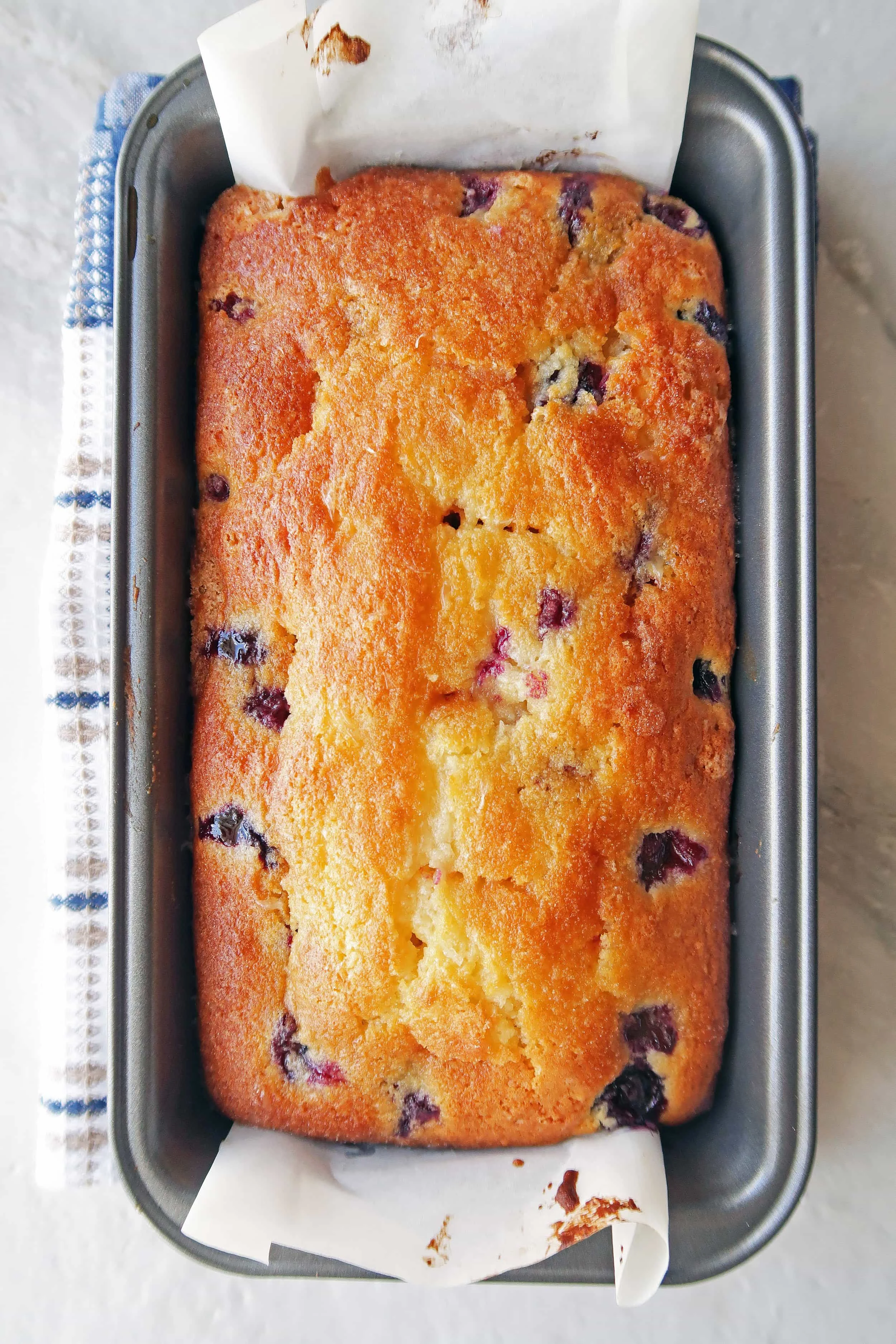 Golden brown Classic Lemon Blueberry Loaf Cake in a loaf baking pan.