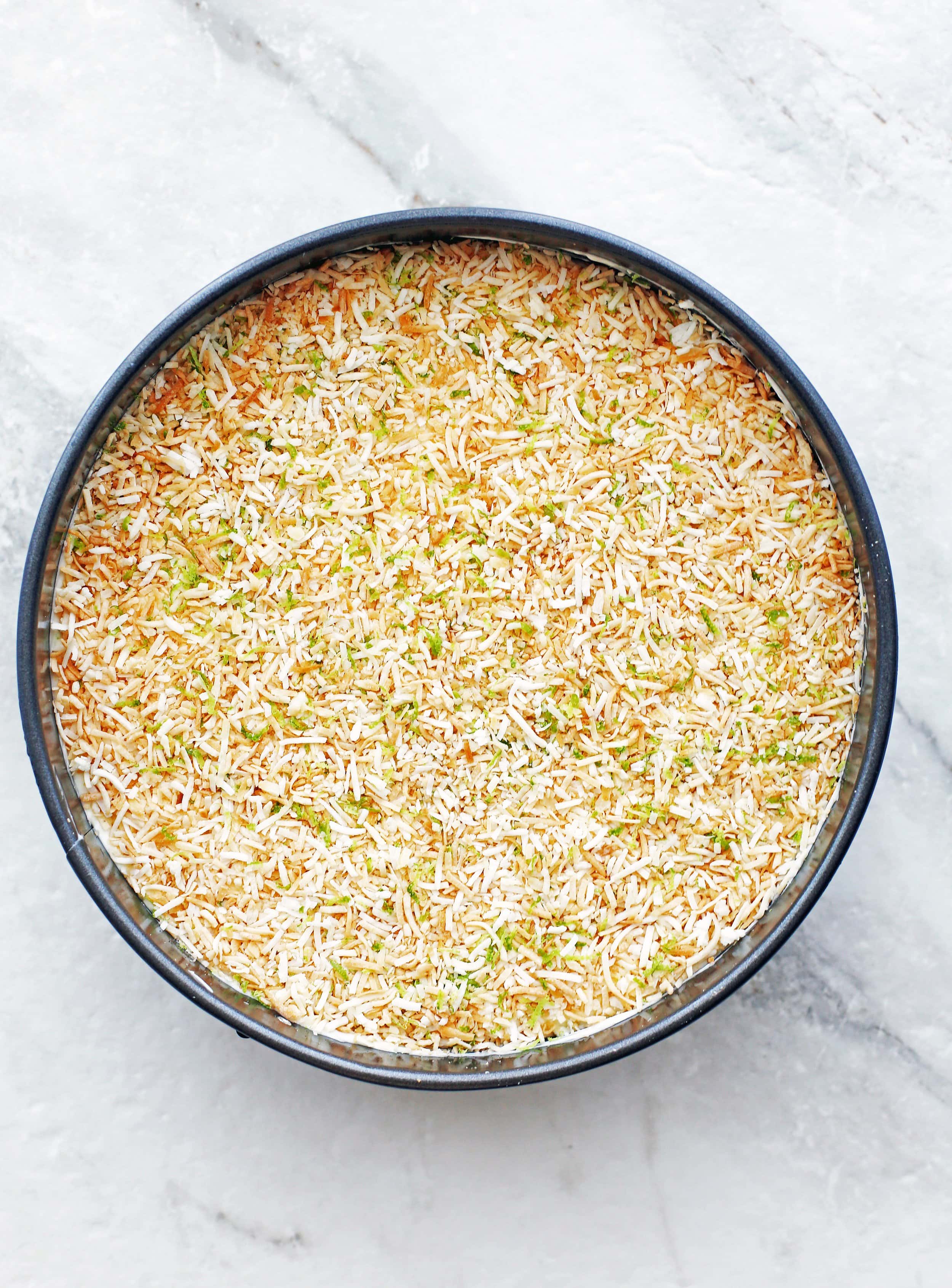 No-bake coconut lime mascarpone cheesecake in a round springform pan.