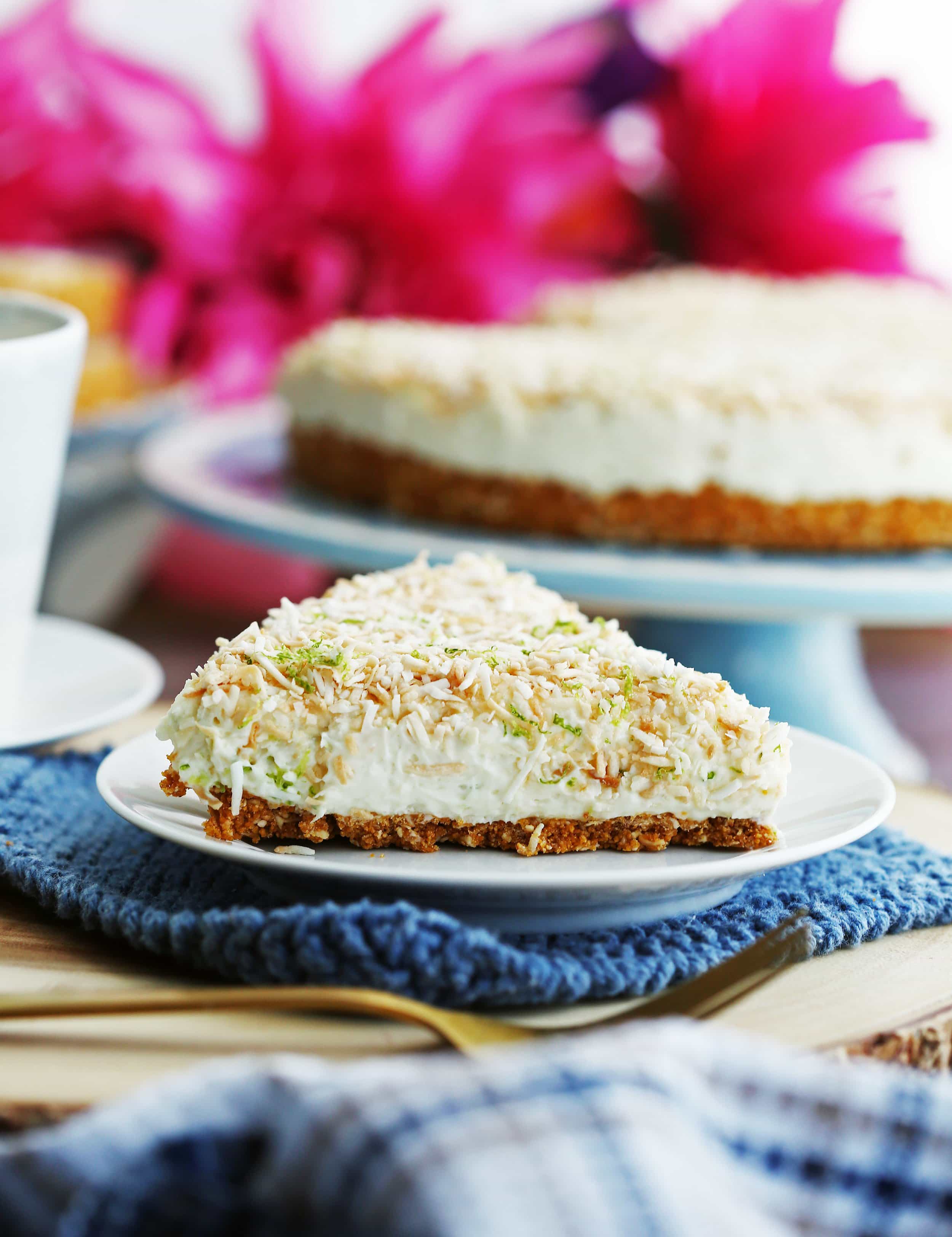 A closeup side view of a slice of no-bake coconut lime mascarpone cheesecake on a white plate.