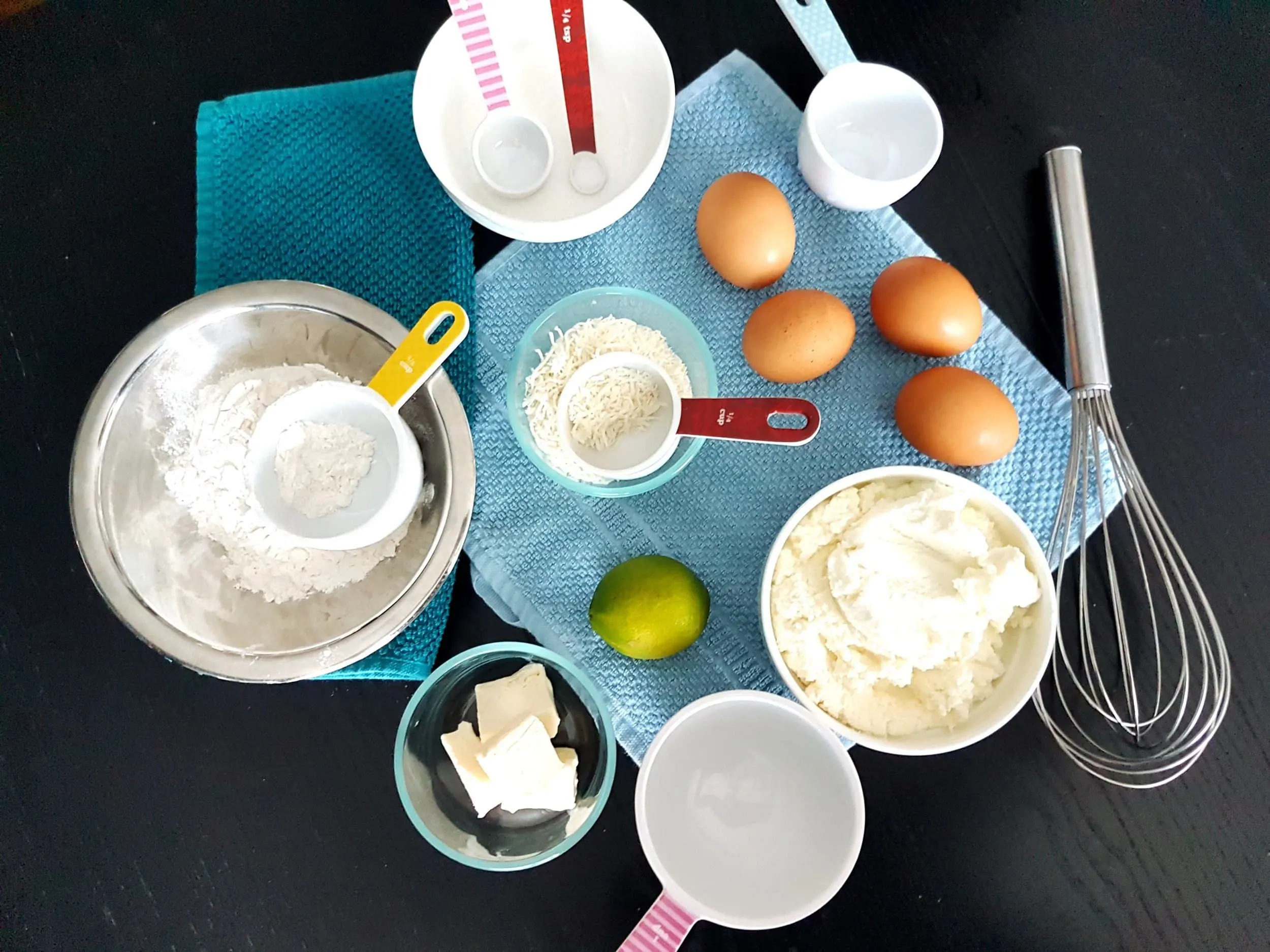Bowls of ricotta, flour, butter, and coconut accompanied by lime and eggs.