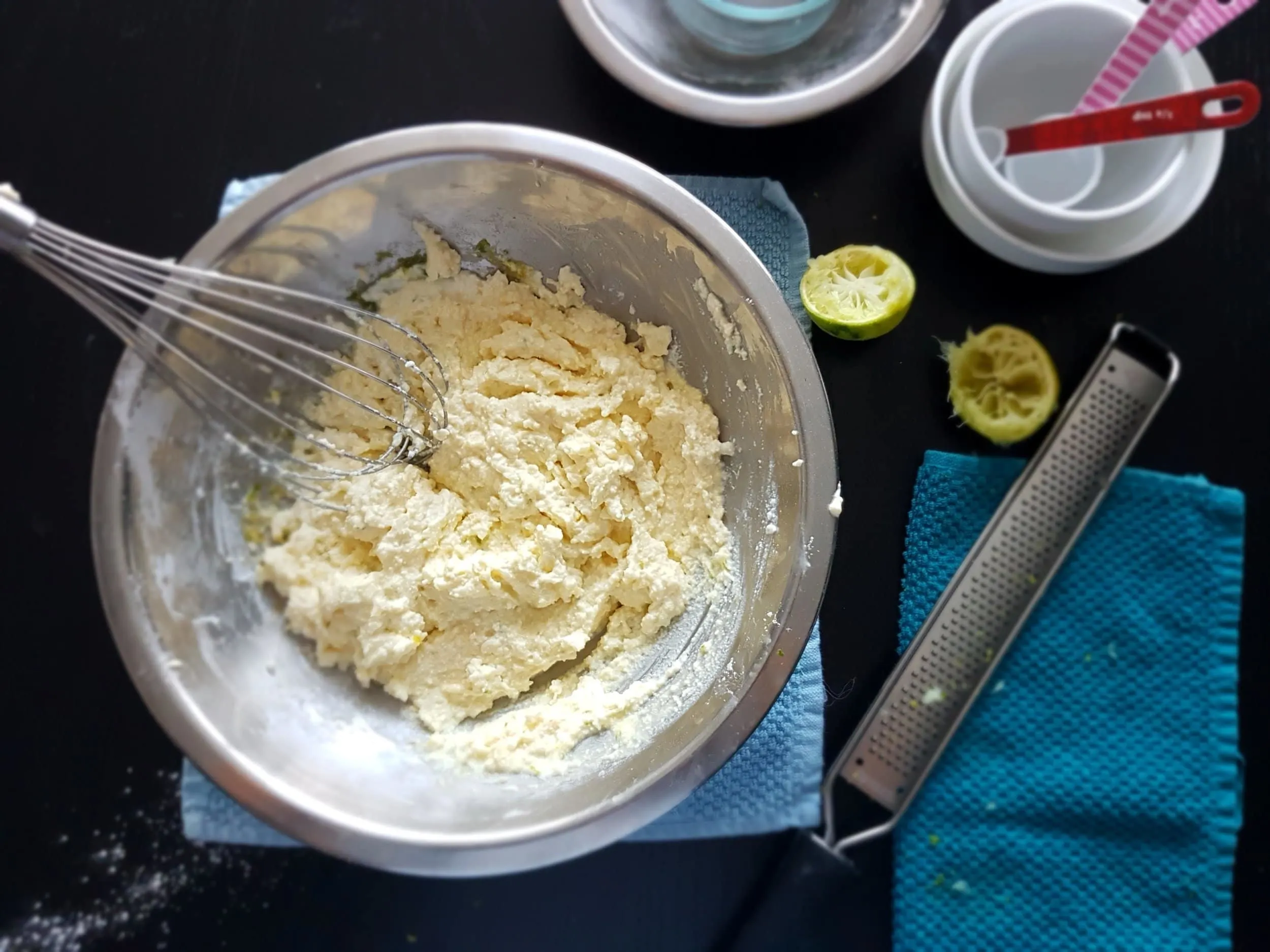 Lime zest being added to egg yolks, ricotta, shredded coconut, sugar, and lime juice.